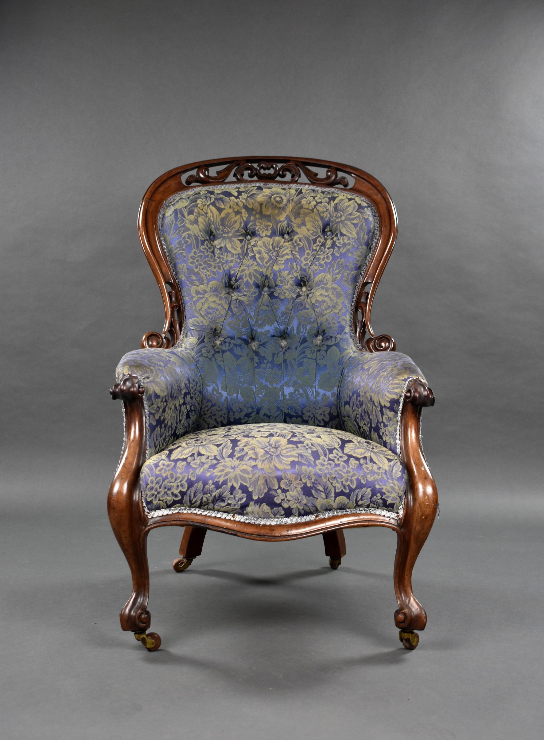 Victorian carved walnut open antique armchair, with button
upholstered spoon back and seat within pierced carved frame with cabriole legs standing on castors.