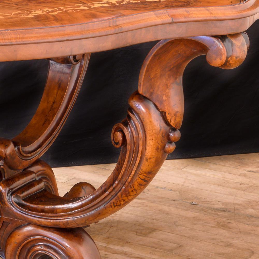 This is an elegant Victorian walnut centre table. The shaped top is beautifully inlaid with adjoined foliage and flowers, all set into quartered book matched burr walnut veneers with fine scalloped edging. All this is sat on a quatrefoil base with