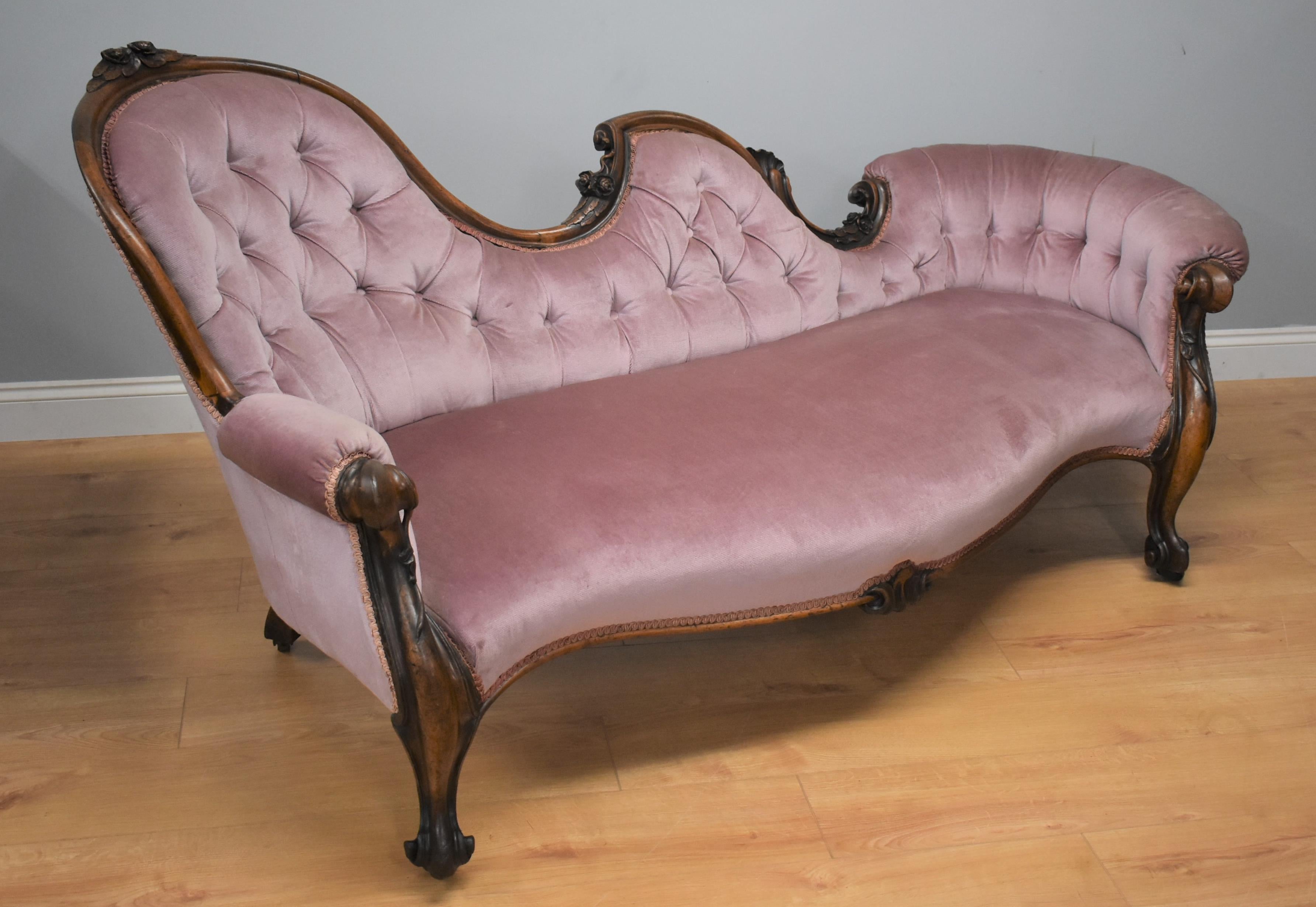 For sale is this good quality Victorian walnut antique chaise in superb condition, with ornate carvings with button back and covered in a lavender fabric in very nice condition, standing on carved cabriol legs on castors. Structurally sound.