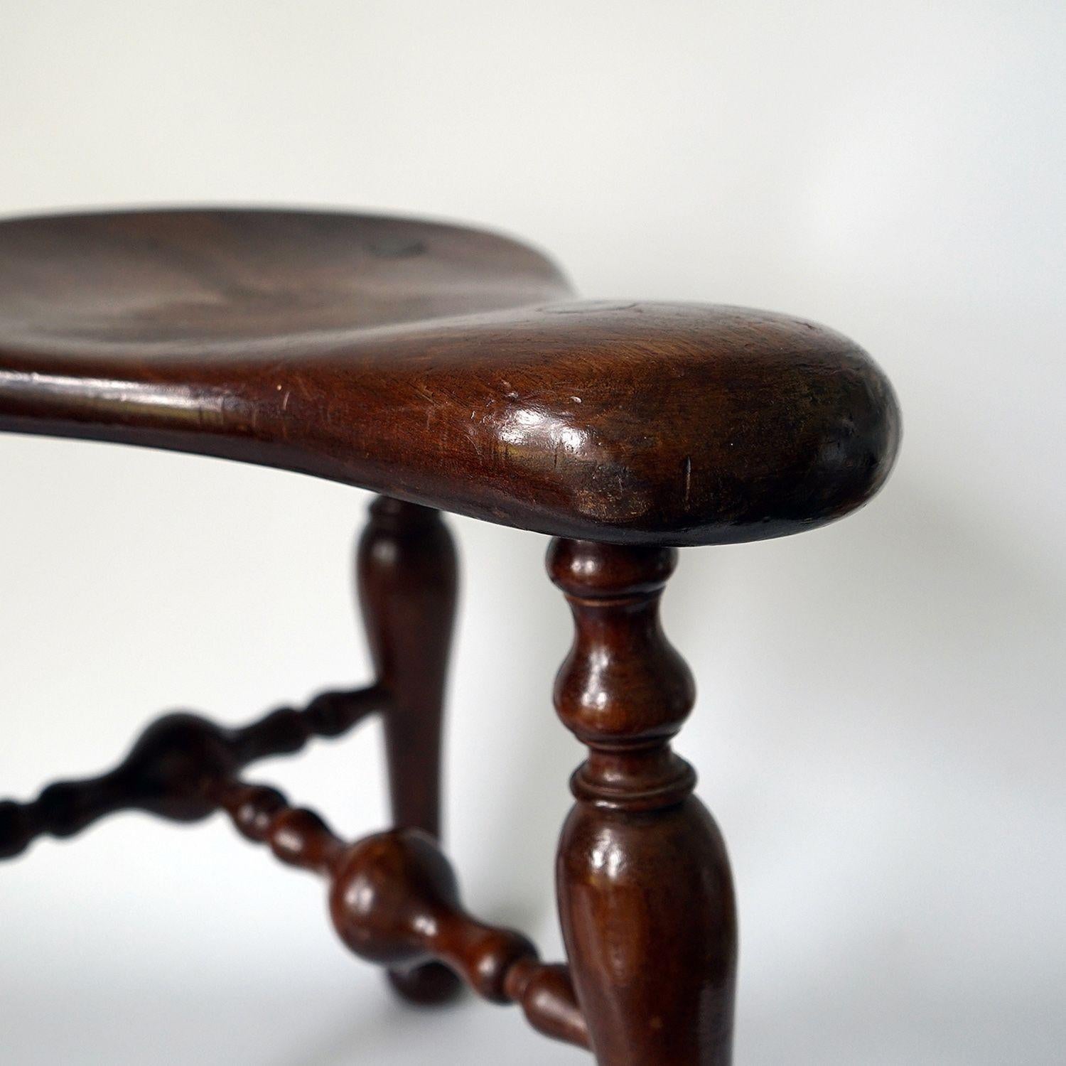 Antique Three-Legged Saddle Stool, 19th Century

Shaped ‘saddle’ seat with turned legs raised on ball feet united by turned stretchers.

Made by Victorian furniture maker supremo Jas (James) Shoolbred.

Impressed registered design number 222356