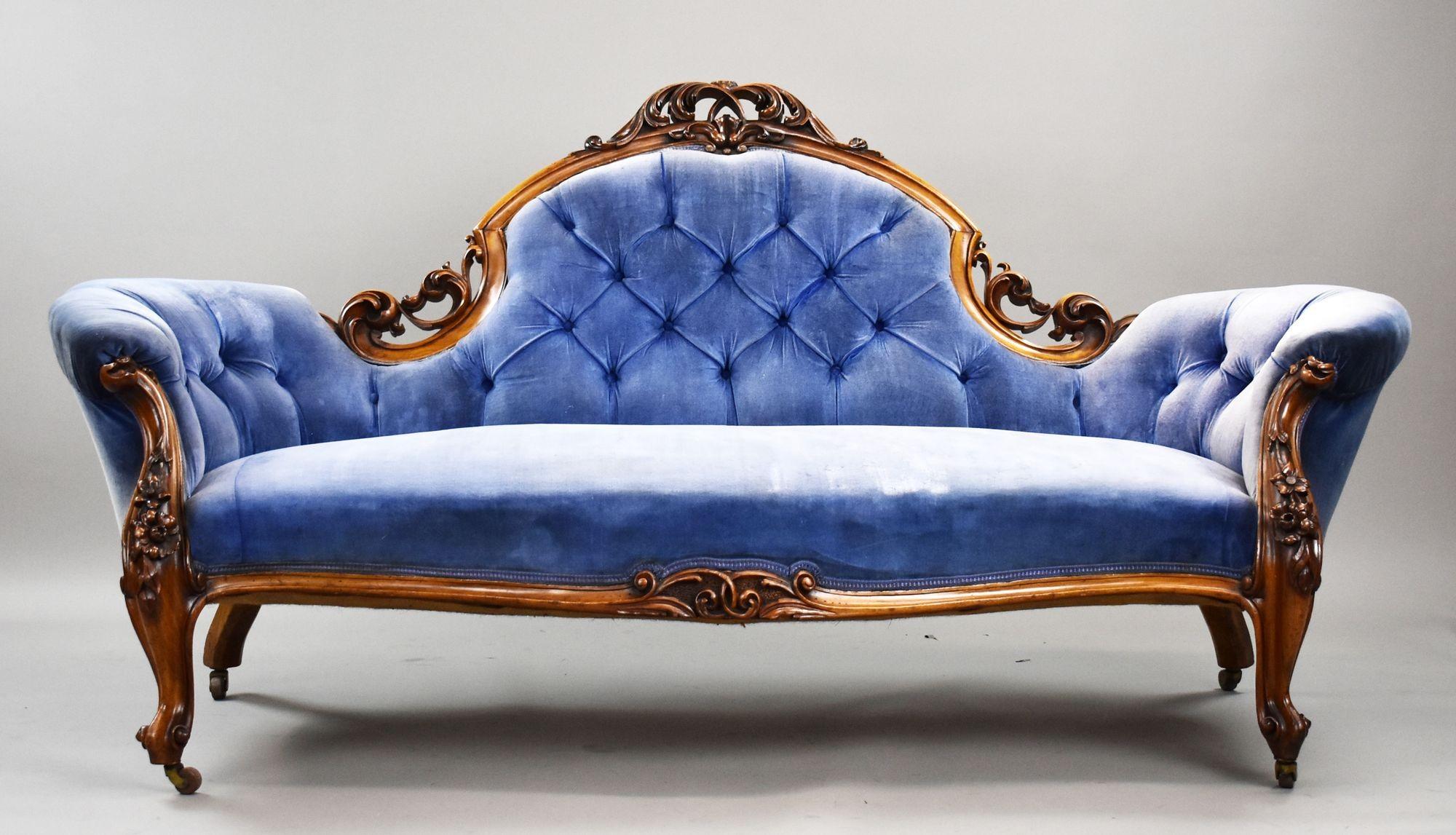 An elegant example of late Victorian craftsmanship, this double-ended sofa is beautifully framed in solid walnut, featuring intricate hand-carved floral and scroll motifs typical of the Rococo Revival style.

The graceful silhouette includes a