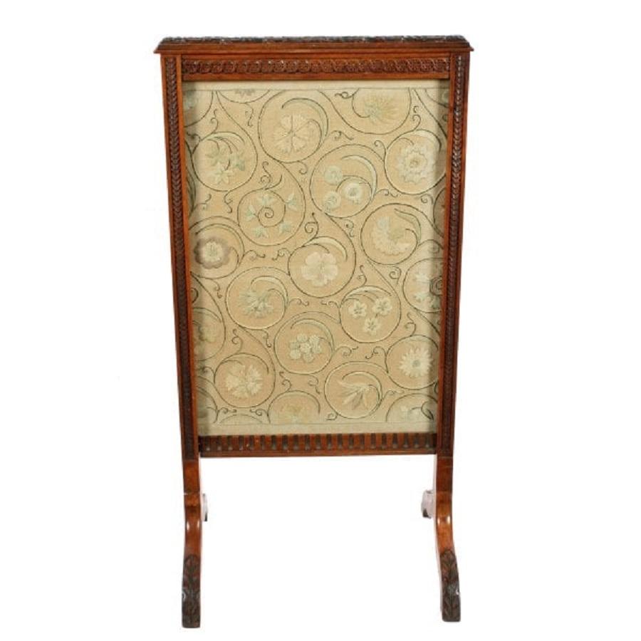 A late 19th century Victorian carved walnut fire screen.

The screen has two pairs of carved supports with carved fish scale and flower decoration to the front.

The front panel is a fine needlework of scrolling flowers behind glass.

The top
