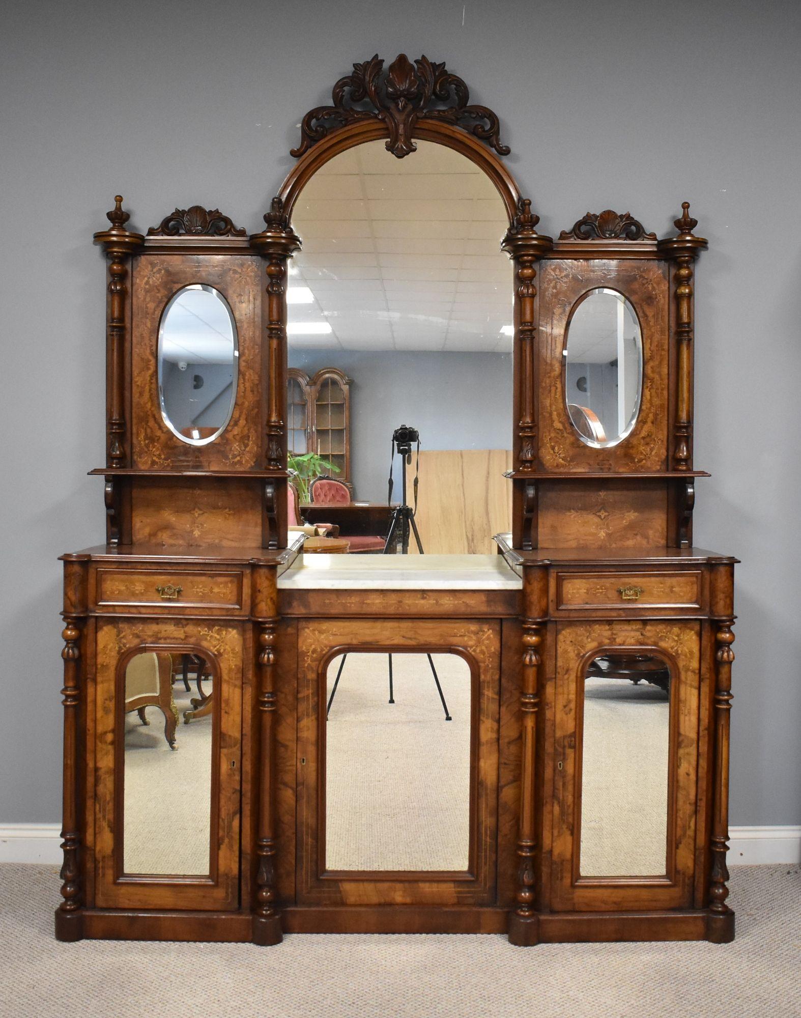 Victorian walnut inlaid mirror back sideboard in good condition with large central mirror above marble top flanked by turned columns above mirror door cupboard with drawers either side above mirror door cupboards standing on plinth base.