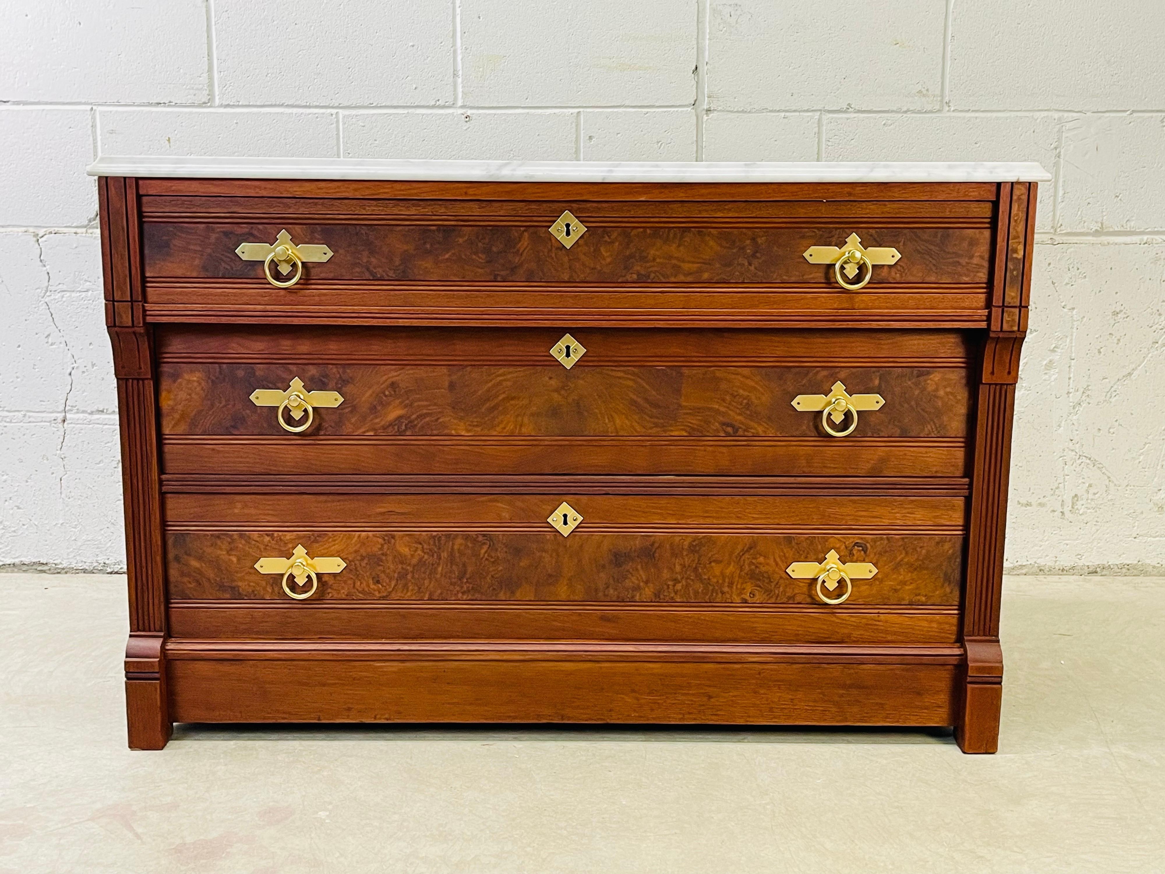 Antique Victorian black walnut wood and marble top low dresser. The dresser has three drawers for storage and brass pulls. Beautiful wood grain with burlwood accent on the drawers. Marked inside with the original paper label.