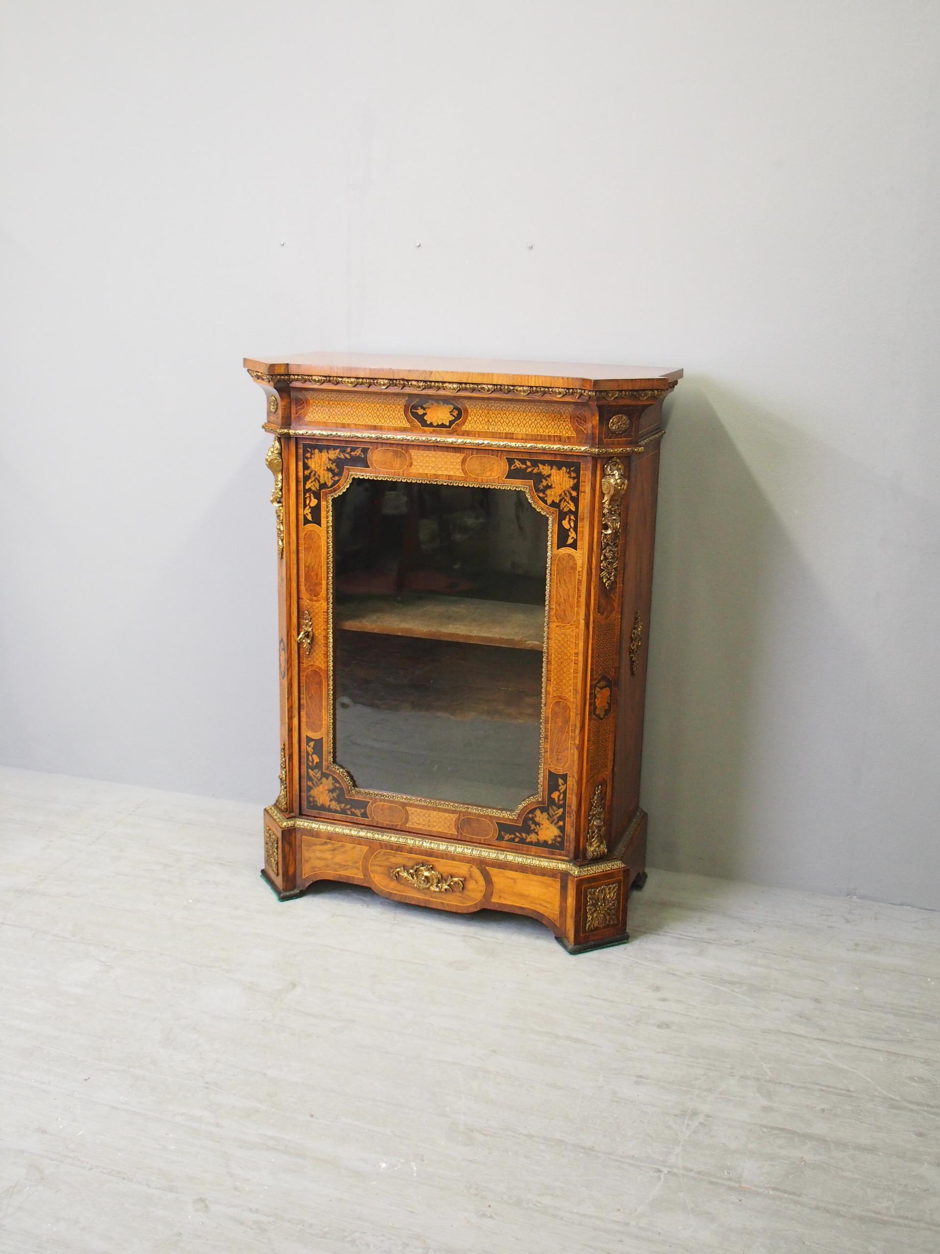 Mid Victorian figured walnut marquetry and parquetry inlaid pier cabinet, circa 1860. The top is in mirror-matched figured walnut with chamfered outset corners, over a frieze with extensive inlaid decoration and ormolu mounts. It has a shaped inlaid