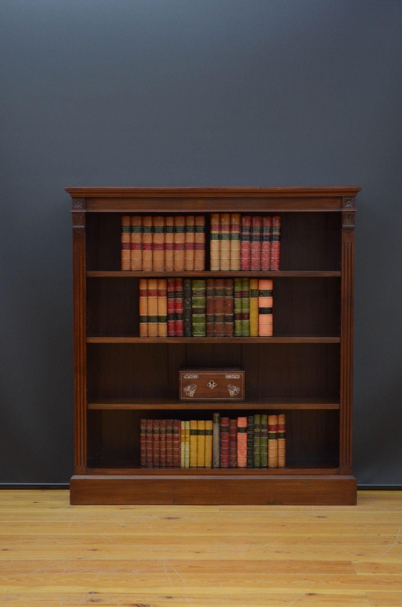 St045 Victorian open bookcase in walnut, having figured top above shallow frieze and three height adjustable shelves, all flanked by reeded pilasters and drop carvings, standing on plinth base. This antique bookcase retains its original finish which