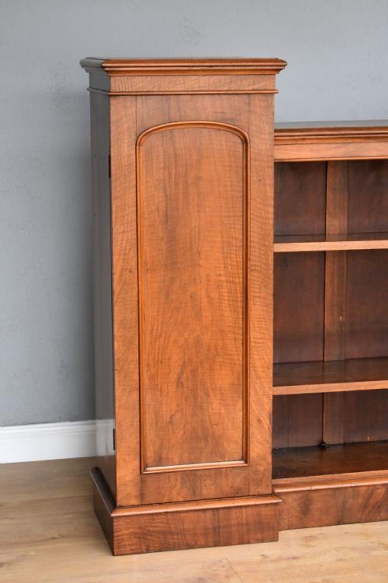 For sale is a good quality and unusual Victorian walnut open bookcase, having a cupboard at each end, fitted with adjustable shelves, with an open bookcase to the centre above a plinth base. The bookcase is in good condition for its age having been