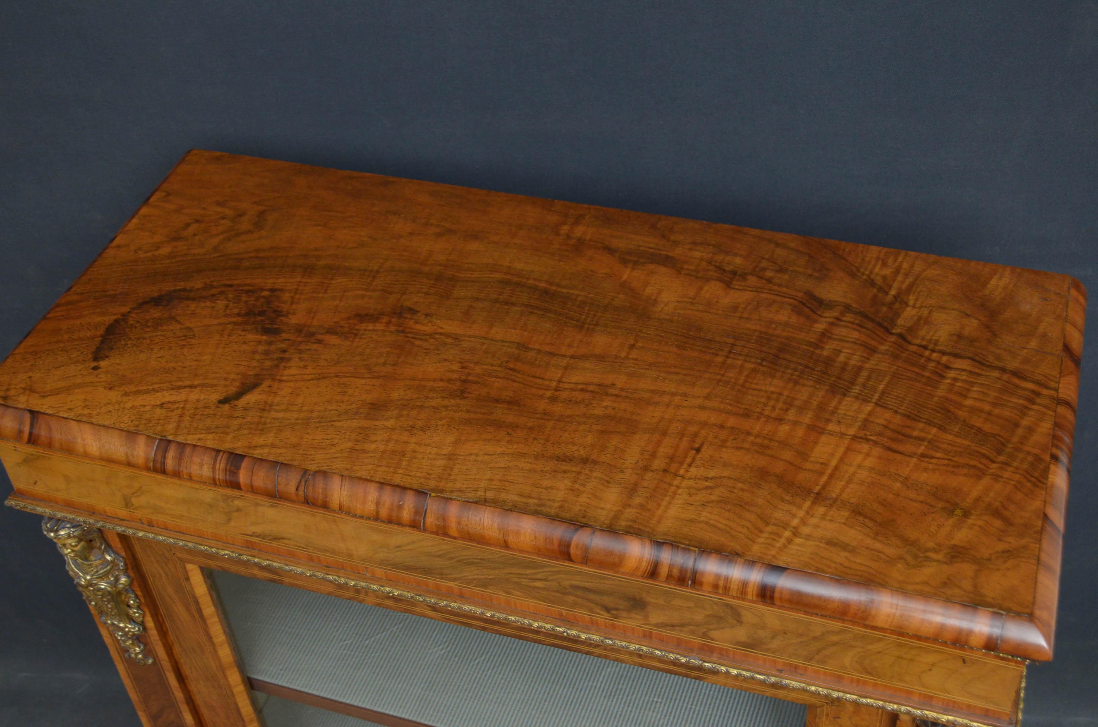 Sn4673, Victorian, walnut, pier cabinet, having figured walnut, moulded top, tulipwood cross banded frieze above satinwood string inlaid door enclosing 2 shelves flanked by Fine quality ormolu decorations all raised on plinth base. This antique