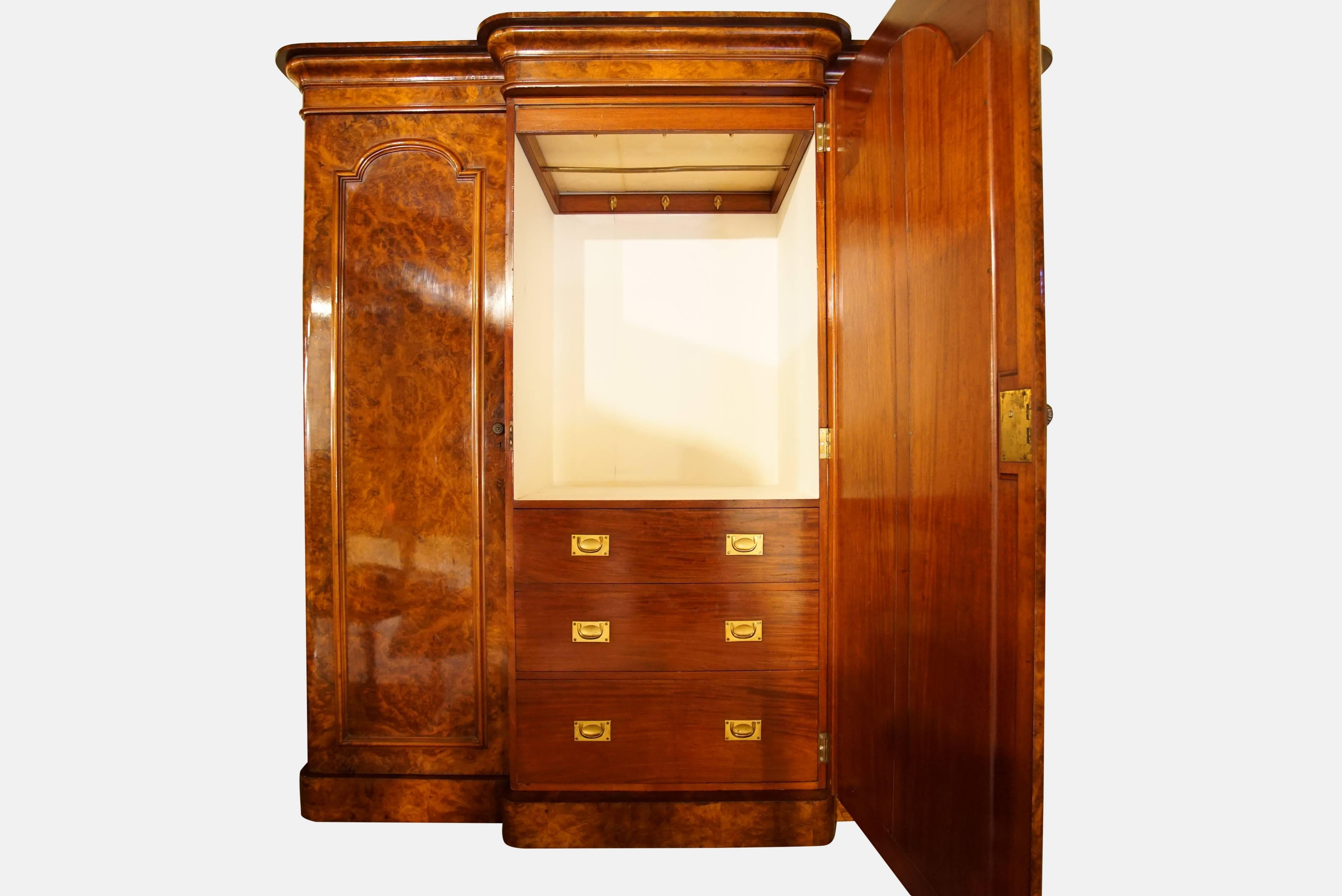 Victorian walnut three-door breakfront wardrobe with molded cornice and plain plinth base. The central mirrored door encloses a fitted interior - a bank of 3 drawers below a pull out hanging rail. The left and right doors enclose a single hanging