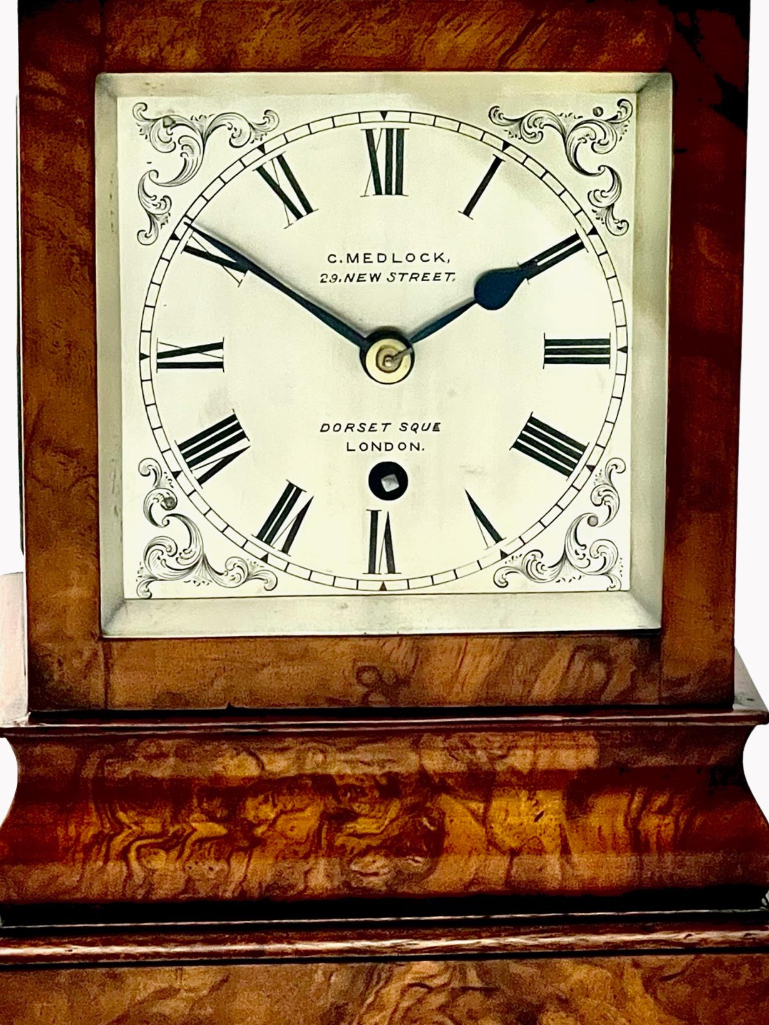 A beautiful English early Victorian 8-day walnut timepiece library clock. The clockmaker is C. Medlock, 29 New Street, Dorset Square, London. Featuring richly figured walnut veneers to the elegant fully glazed case and an engraved and silvered dial