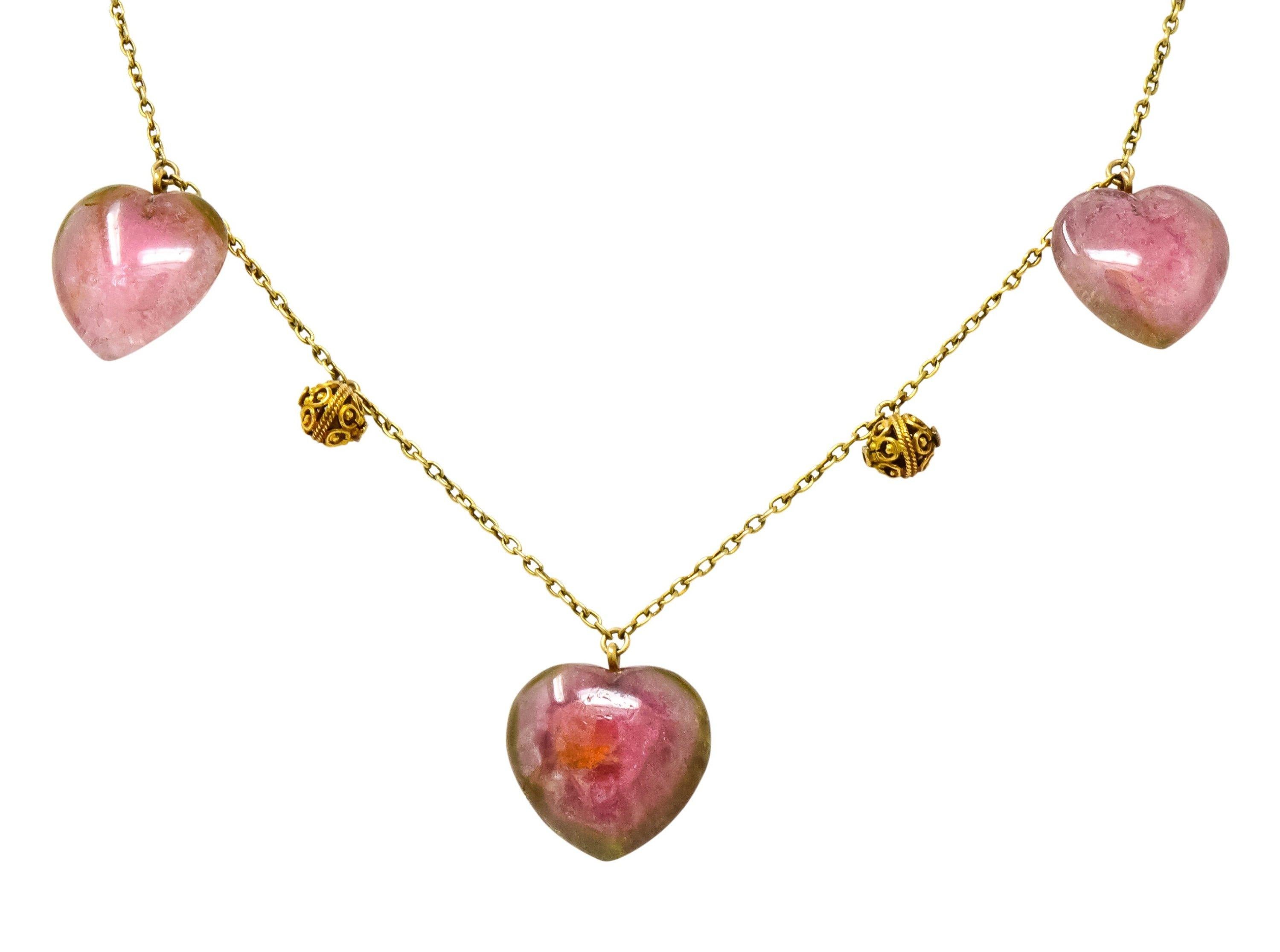 Designed as a cable chain necklace featuring five watermelon tourmaline heart drops

Each centering a saturated pink color surrounded by fresh green color; translucent with natural inclusions

Alternating with articulated gold balls decorated with