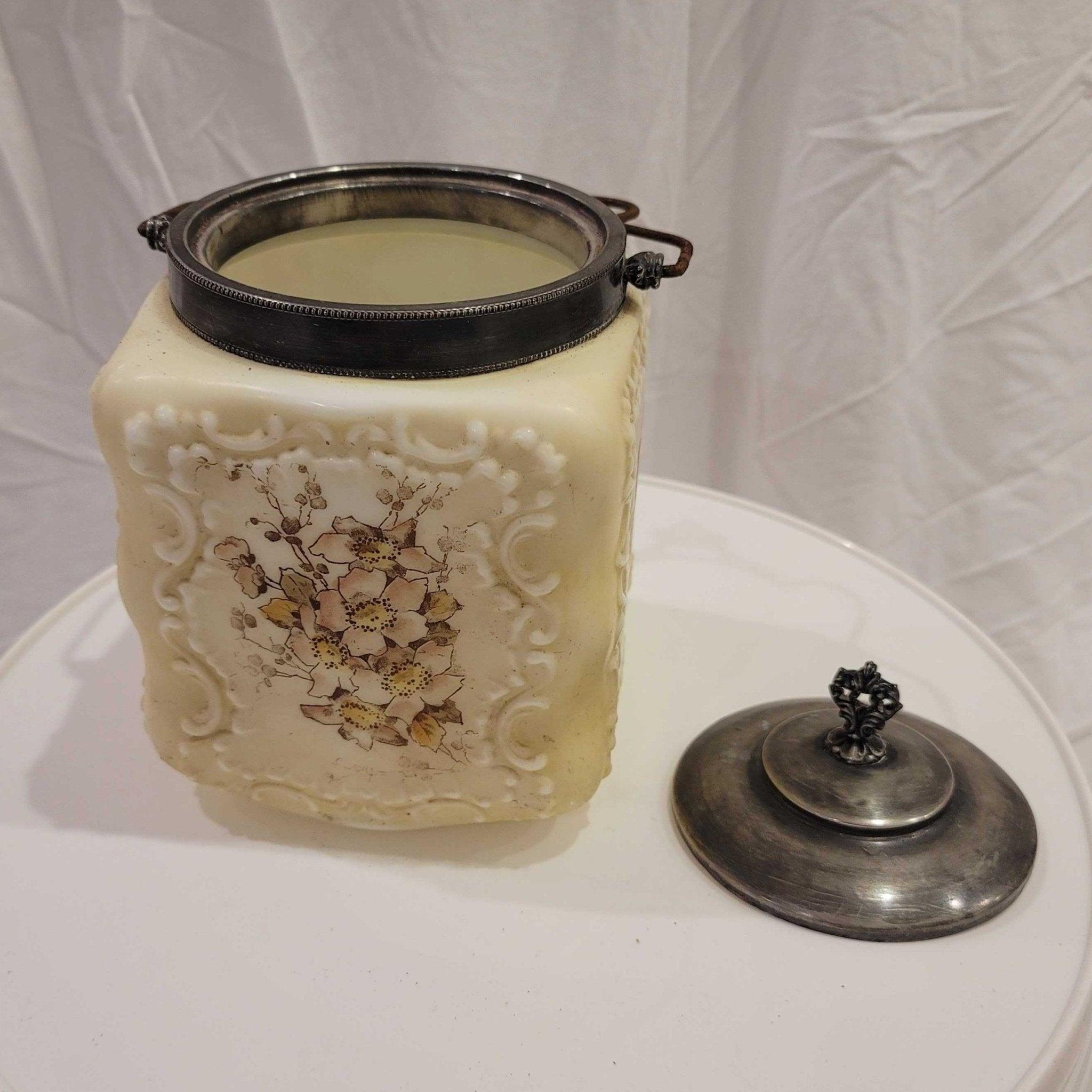 Antique Victorian Wavecrest biscuit holder with milk glass base and painted floral detailing. 

 Commonly referenced as a Mt. Washington piece, the milk glass body shows a yellowing due to age, with a floral imprint on each of the flat