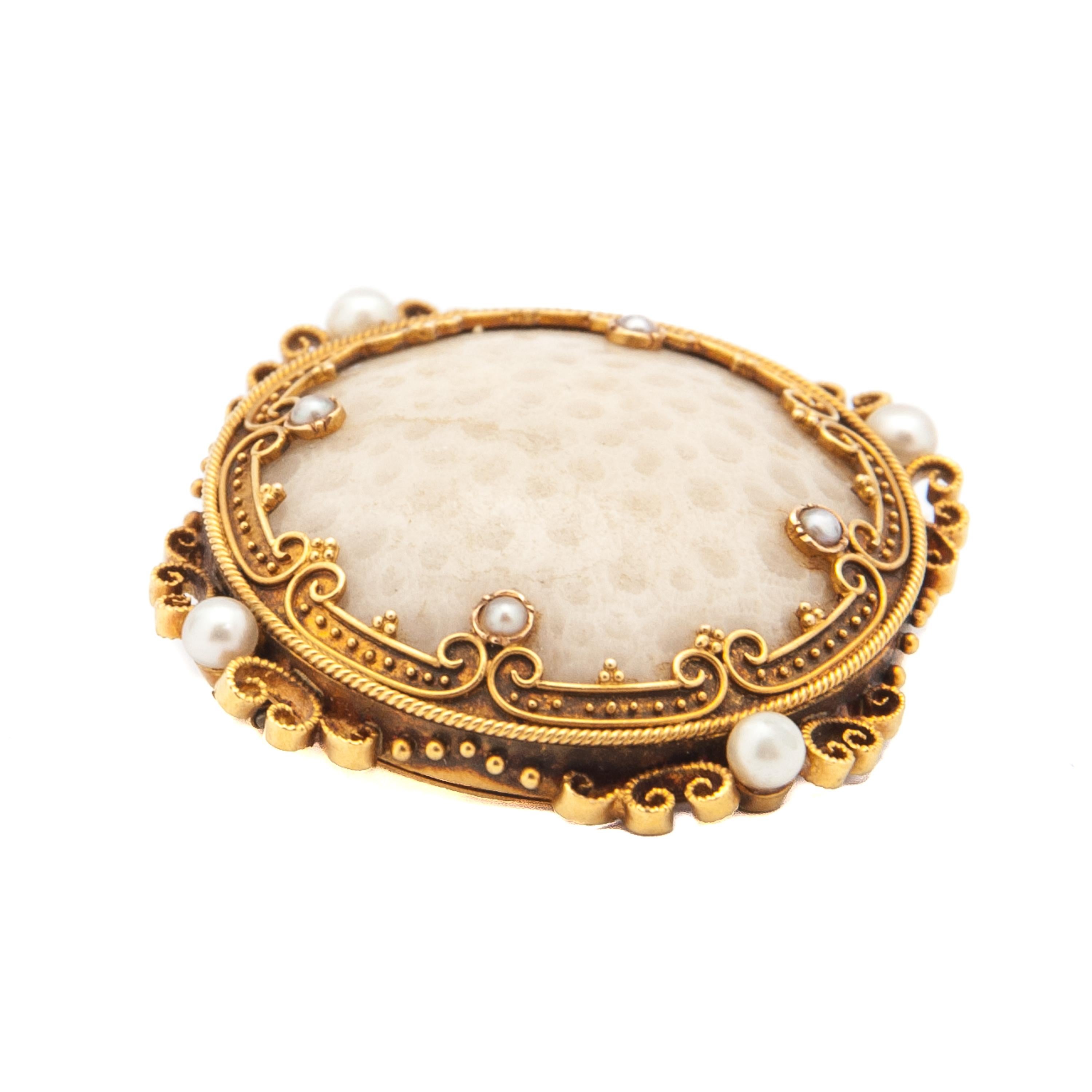 This is an antique 19th century fossilized white coral brooch set with eight seed pearls. The fossilized coral and pearls are set in an 18 karat gold round worked frame. The frame of the brooch is designed with a rope motif, curls and pearls,