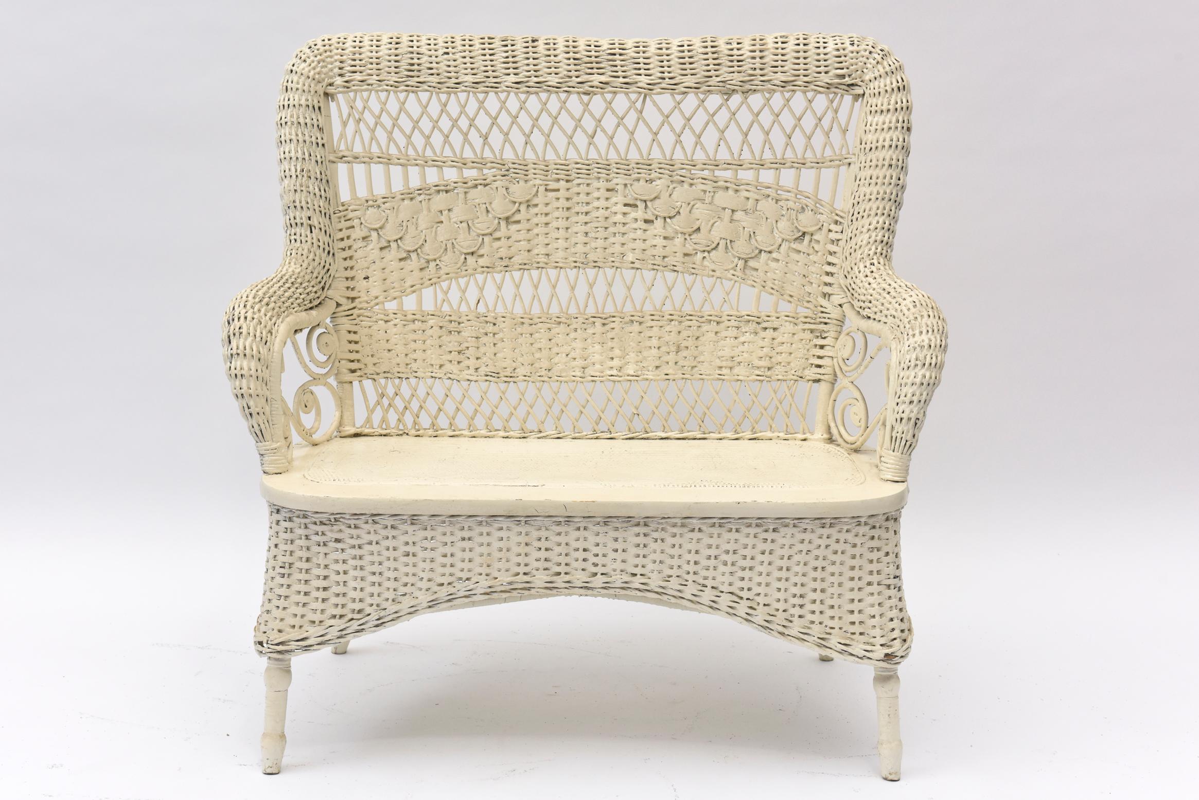 Part of a large collection of ornate Victorian wicker that was collected over the years by a Senator's wife. This rolled woven arm loveseat has wicker curlicues in the open areas under the side arm rests. Across the back are alternating lattice