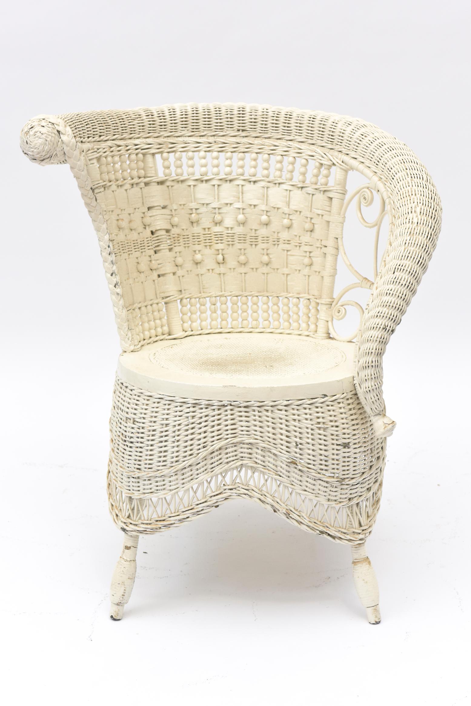 Part of a large collection of ornate Victorian wicker that was collected over the years by a Senator's wife. Elegant wicker portrait chair with rolled arm incorporates beading, lattice work, woven skirt, and woven beaded front legs. Whether it is