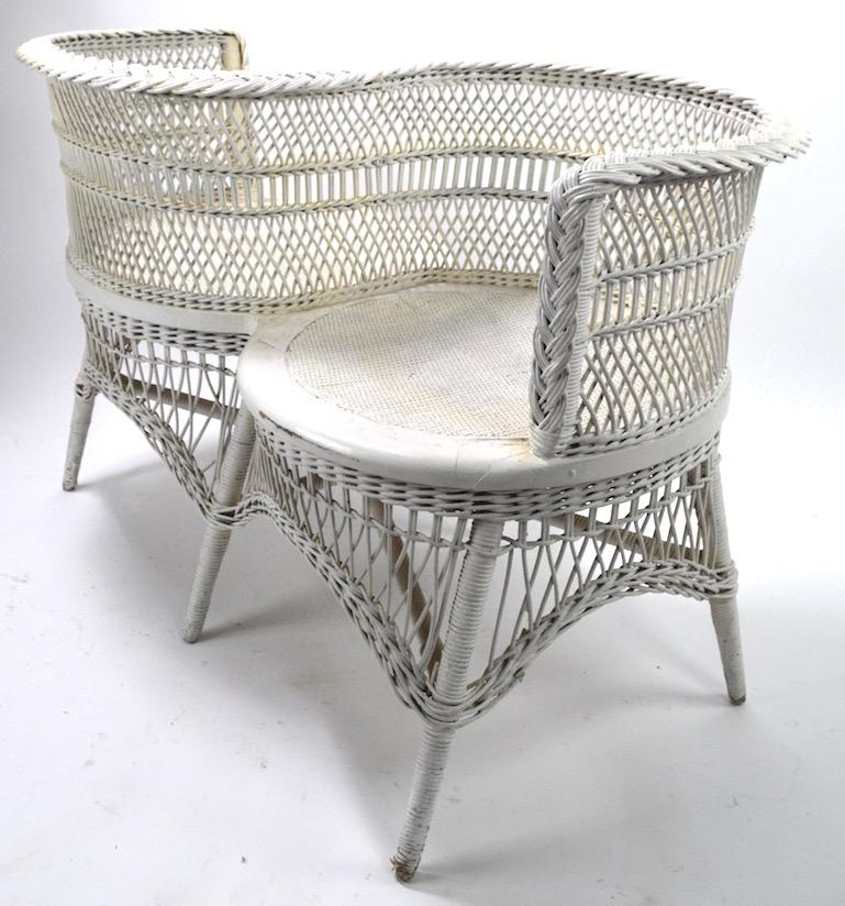 Stylish and sexy Victorian period wicker Tete a Tete, Classic and dramatic form, hard to find example. This piece is in very good, original condition, it is in later, but not new, white paint finish which shows some cosmetic wear, normal and