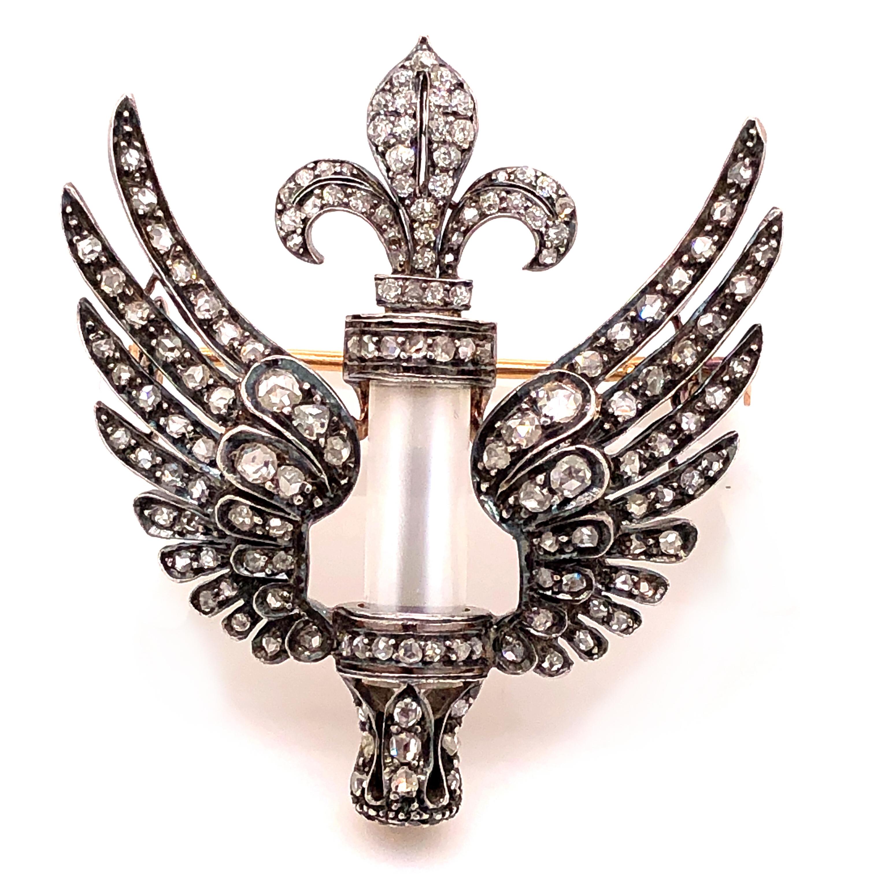 A mesmerisingly beautiful Victorian brooch with old and rosecut diamonds, 1880s. The brooch, which can also be worn as a pendant, depicts two wings that centre a cylindric moonstone between them. A fleur-de-lys sits on the top of the brooch. The