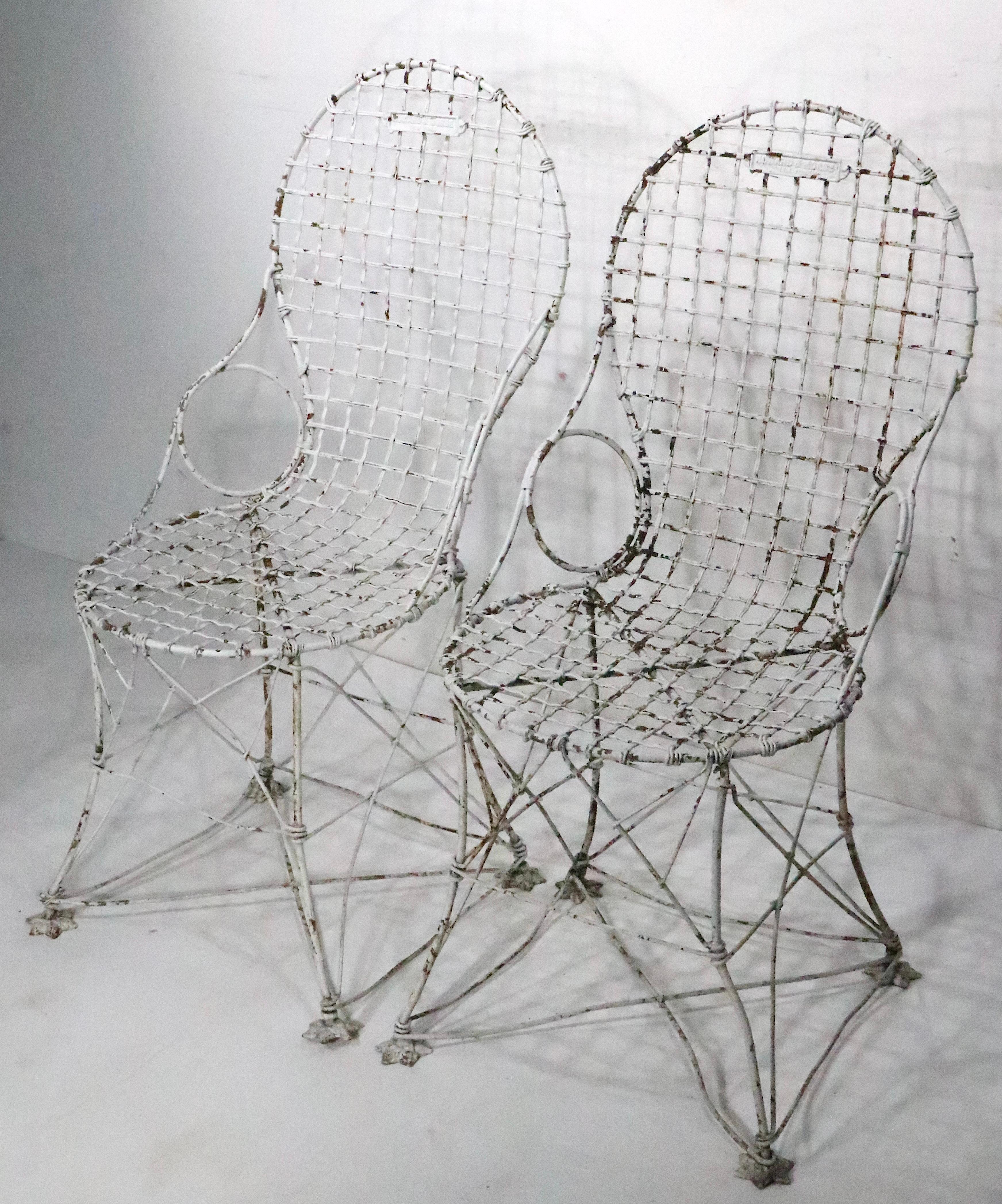 Exceptional antique wire garden, patio chairs, by noted maker Howard & Morse New York circa 1800/1880. The chairs retain the cast iron markers tag, and have interesting cast star form feet.  Both chairs are in very good, original, ready to use