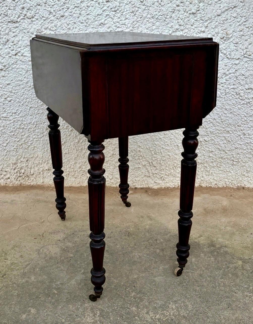 This elegant 19th-century Victorian drop-leaf side table is crafted in richly toned wood, showcasing the warm colour and fine grain characteristic of the period. The table features two practical drawers with original wooden knobs and beautifully