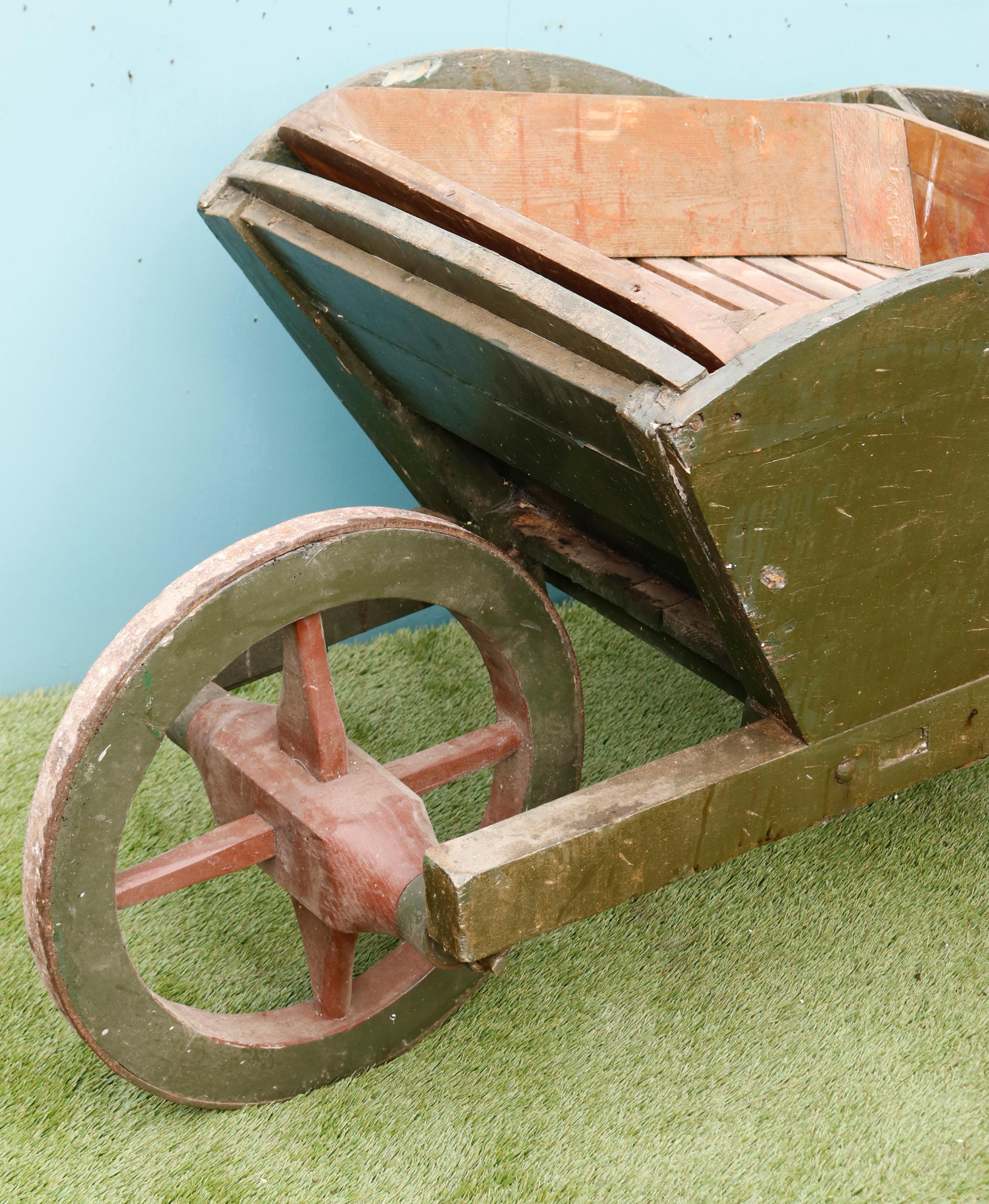 An antique painted timber wheelbarrow. Later adapted with a tray for carrying apples.
