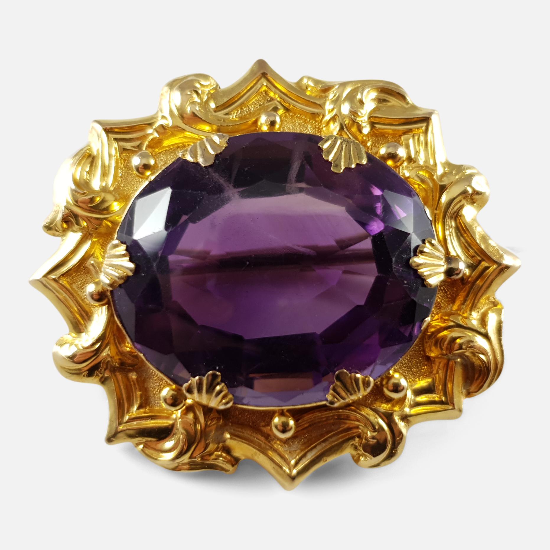 Description: - This is a fine antique Victorian 18 karat yellow gold amethyst mounted brooch. The large oval-shaped amethyst is set within a stylised foliate, octagonal-shaped border, in yellow gold. As was common for the period the brooch is