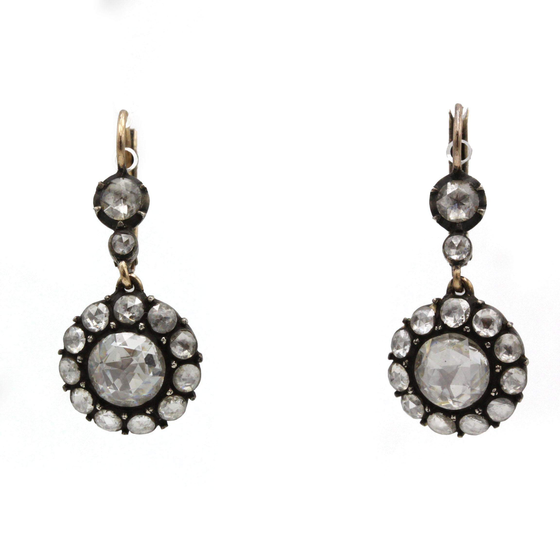 Ces élégantes boucles d'oreilles en forme de goutte datant du 19e siècle témoignent du raffinement victorien et de la délicatesse de leur mise en scène. Chaque boucle d'oreille est ornée d'un diamant central taillé en rose, encadré d'un halo de