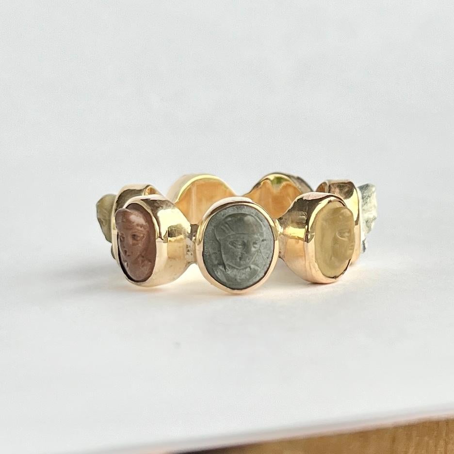 This yellow metal ring has carved faces set within it.

Ring Size: N 1/2 or 7  
Band Width: 9mm

Weight: 3.8g