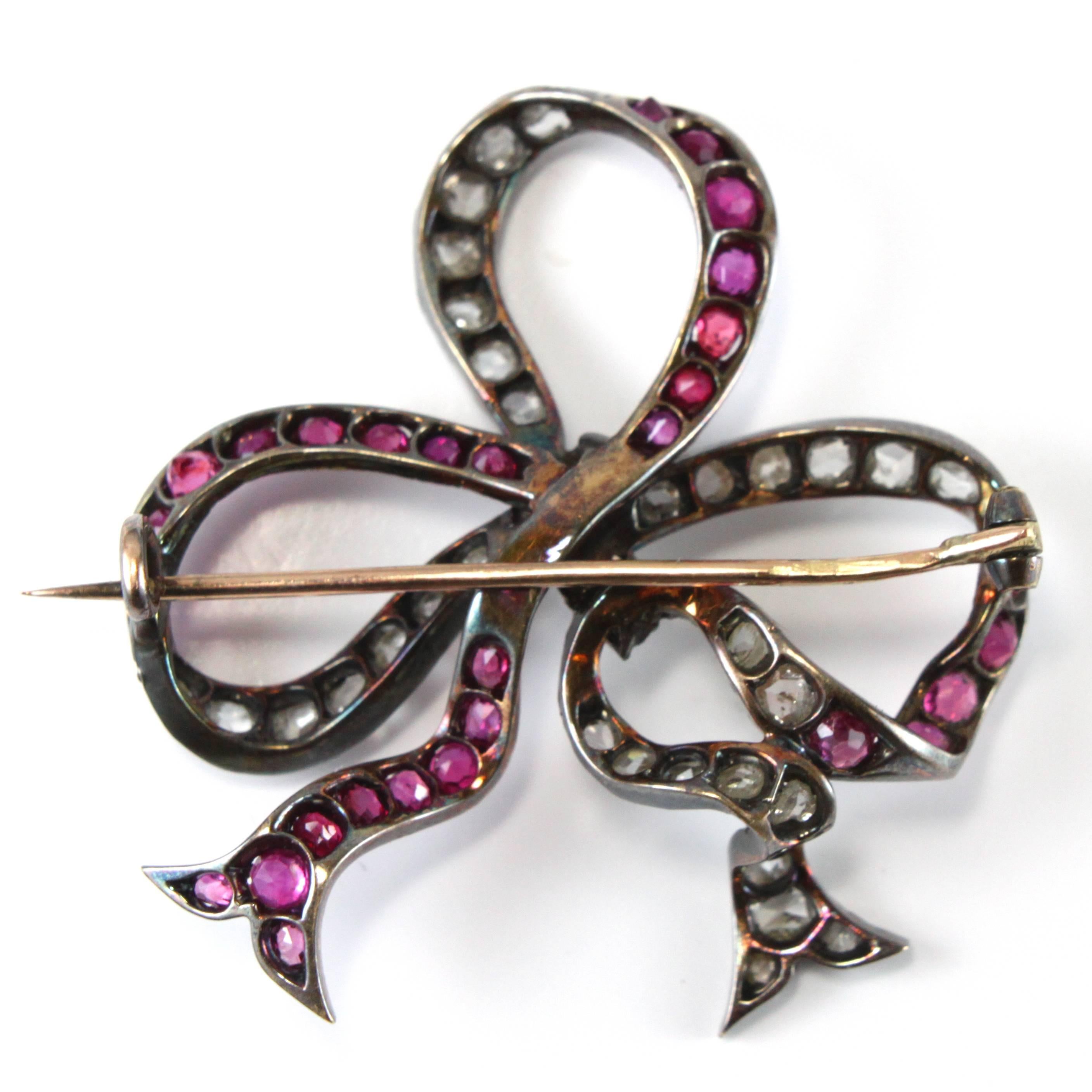 A beautiful Victorian ribbon bow brooch set alternating with rubies and diamonds in silver and gold.
