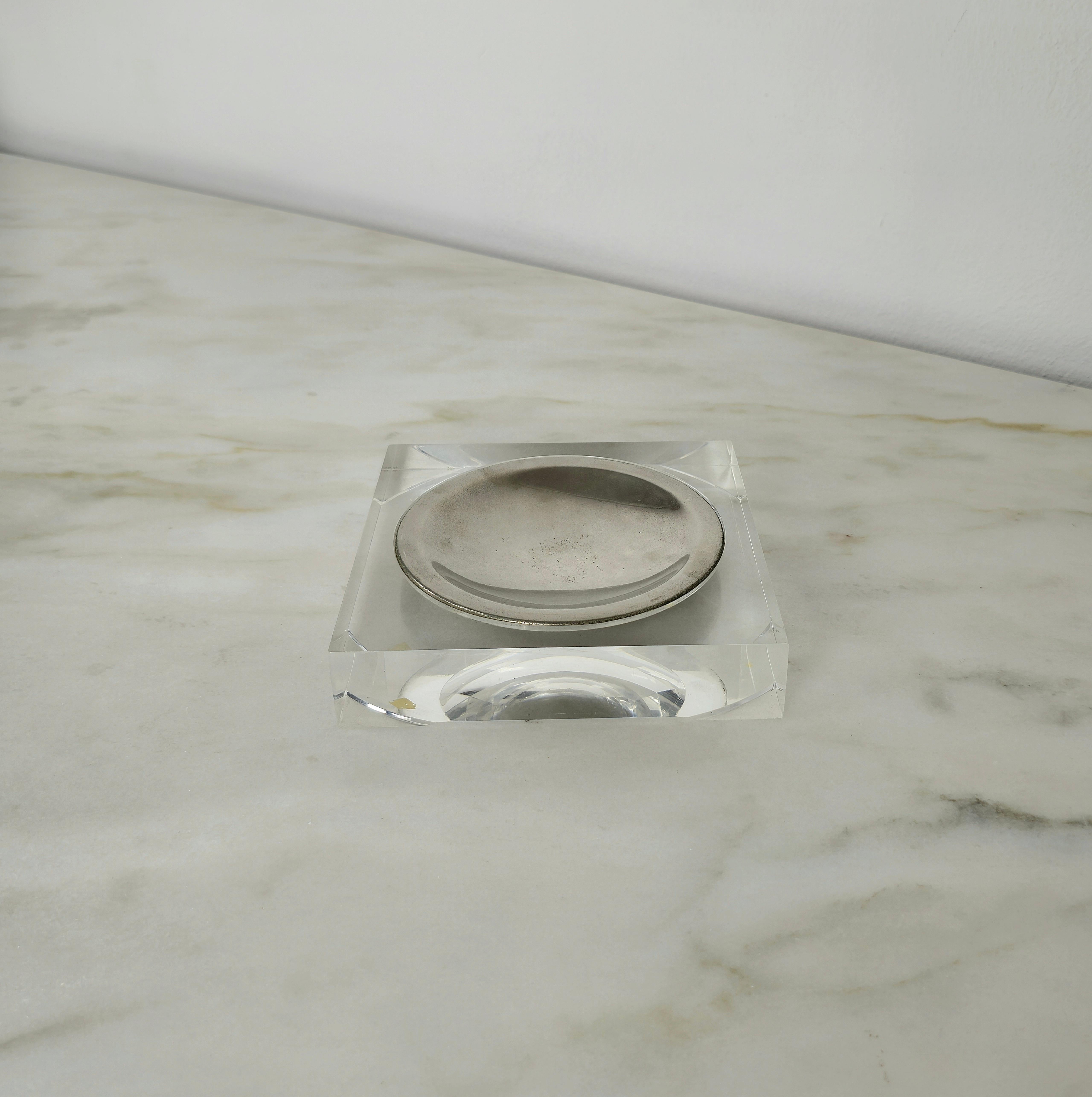 Vide-poche produced in the 70s by the famous Christian Dior clothing and accessories house.
The square-shaped pocket emptier was made in lucite with the underlying corners in relief, as if they were feet. concave central plate in chromed