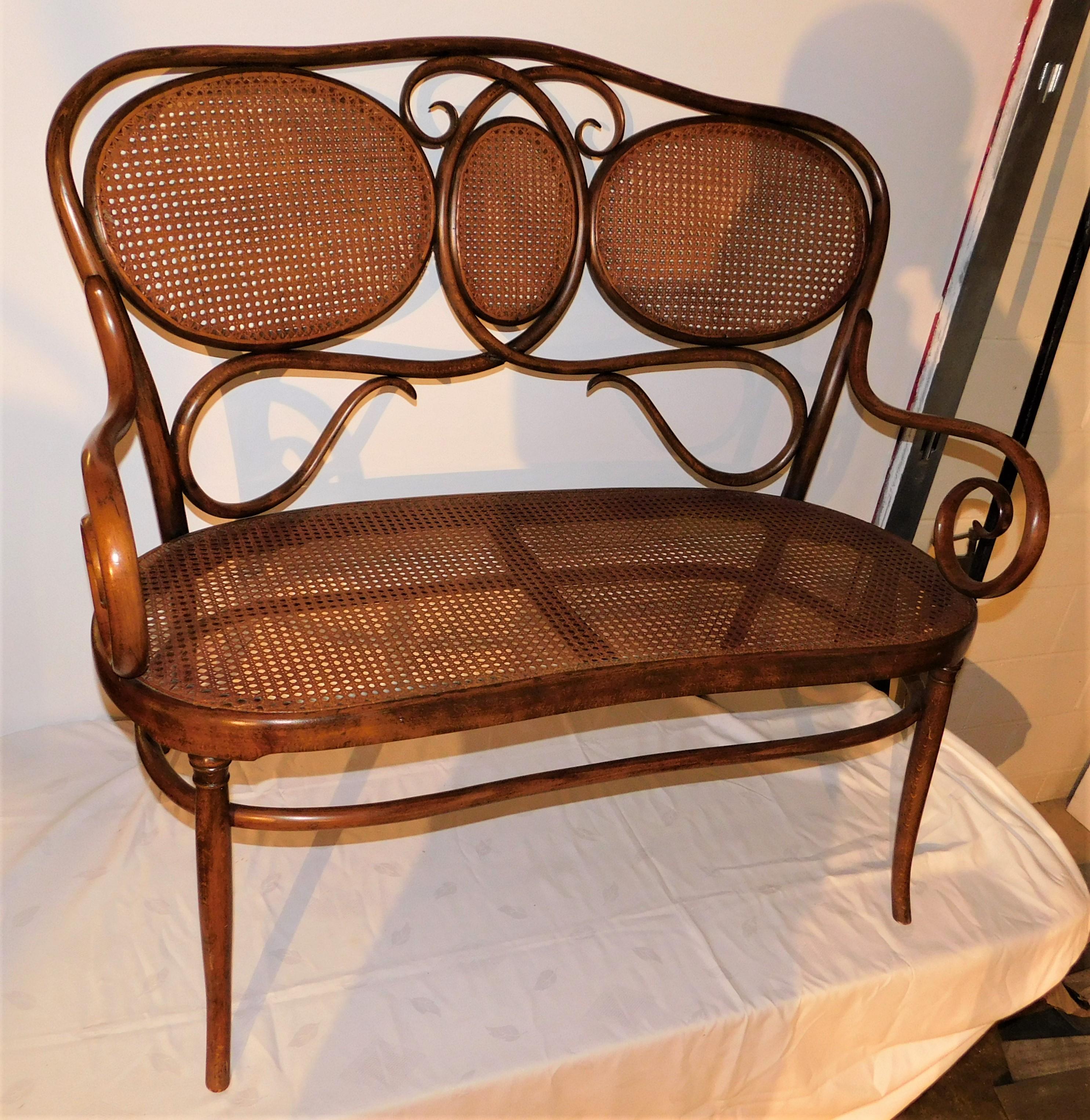 Banc ou canapé en bois courbé de la marque Thonet. Assise et dossier cannés en forme de rein avec un cadre en bois courbé. Design/One de la fin du 19e siècle, originaire d'Autriche, l'étiquette d'expédition sur le dessous montre qu'il a été envoyé à