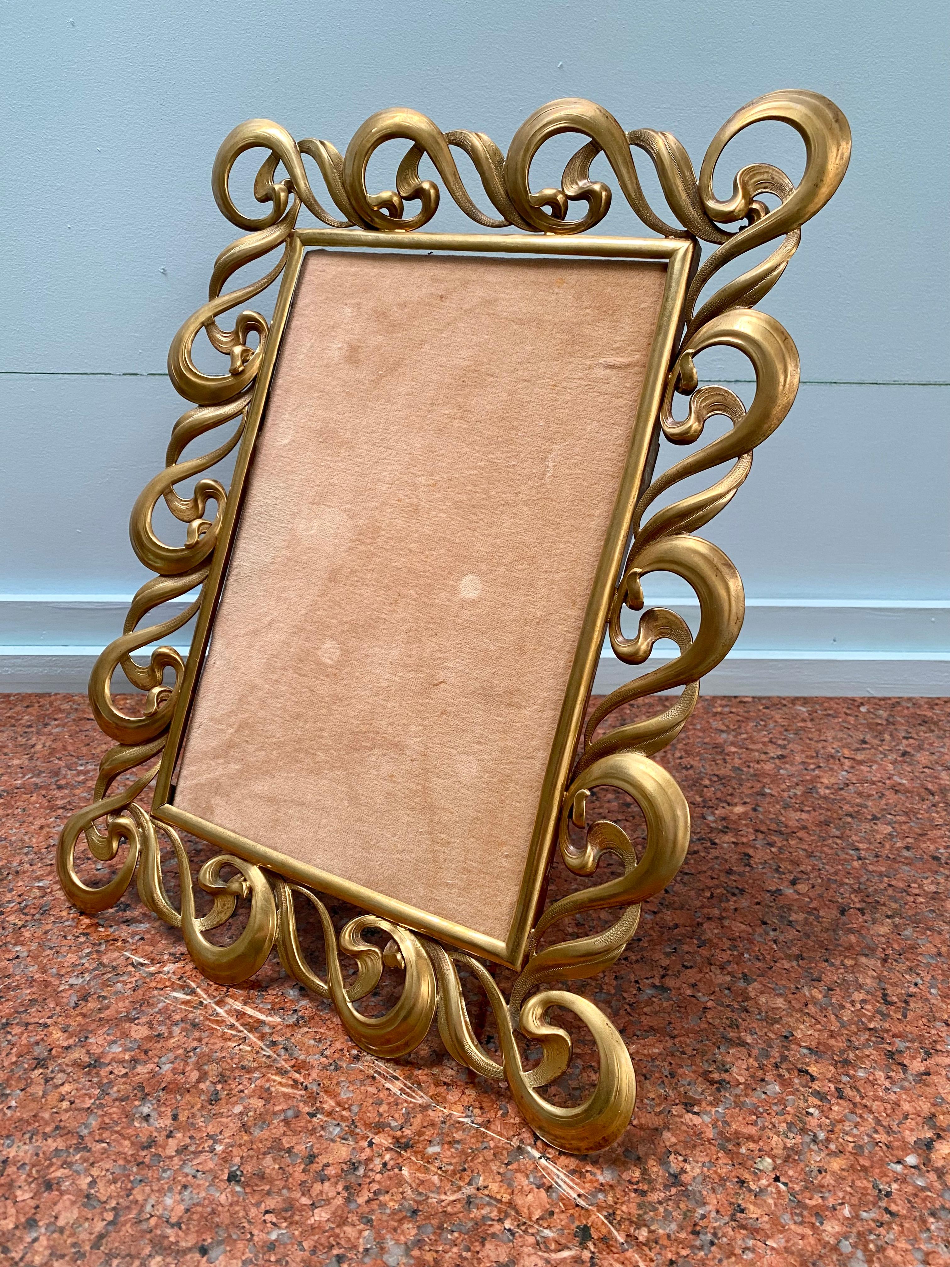 Large Art Nouveau easel portrait picture frame of fine pressed brass. New ply backing with original camel velvet. Hand and machine made factory production, probably English, from the early 20th century. 

This highly decorative frame is large enough