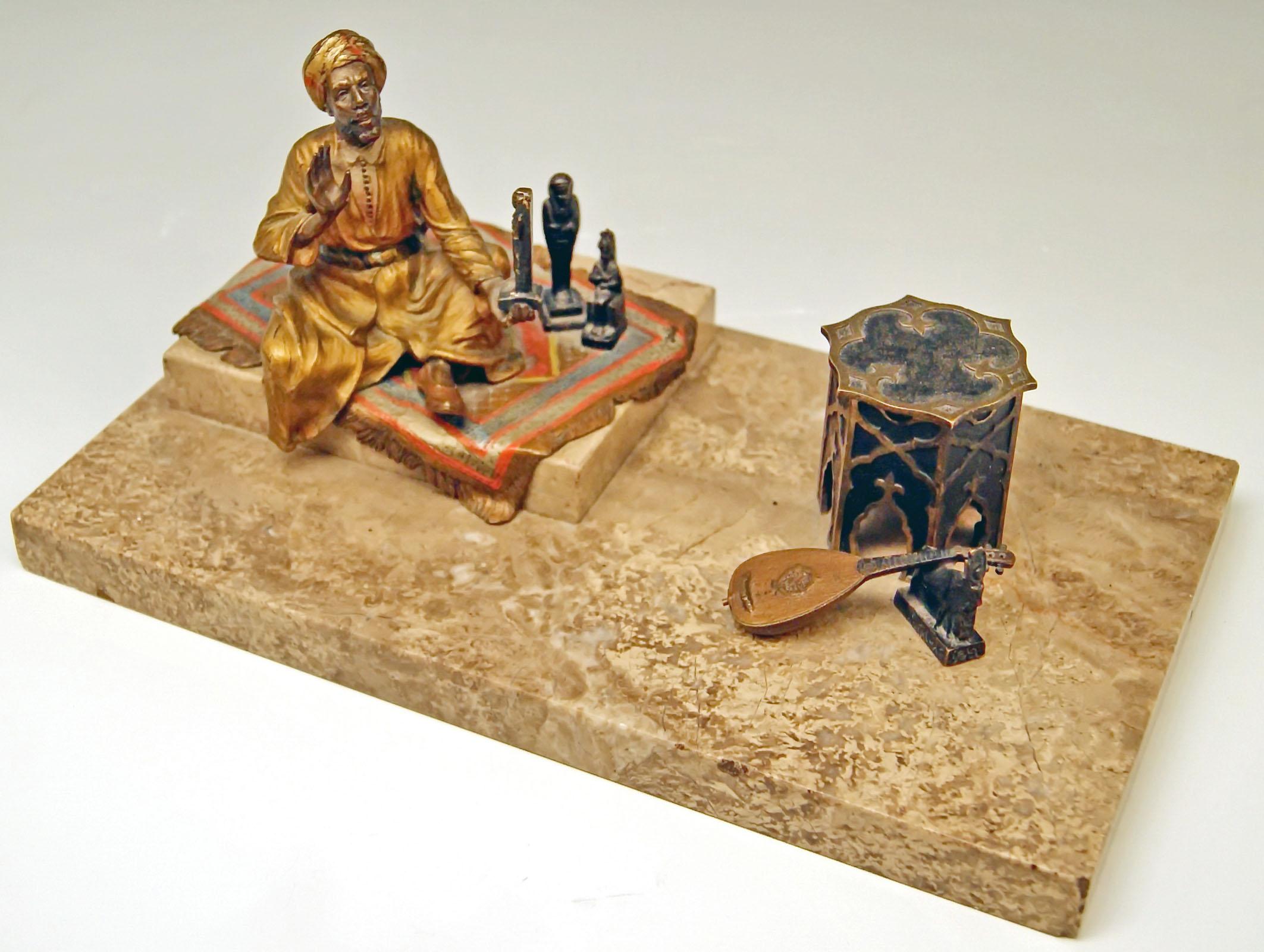 Stunning bronze figurine group: Arab man clad in mantel (fireplace) selling Egypt antiquities.
An Arab man with turban is busy with presenting Egypt figurines to spectator: 
The man has taken place on a carpet which was put on rectangular marble