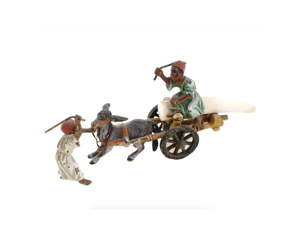 Groupe de figurines en bronze coulé peint à froid et matériaux naturels, de style oriental viennois. Le groupe figuratif représente une scène avec deux garçons arabes qui se disputent, l'un d'eux étant assis sur un chariot tiré par un âne. Réalisé à