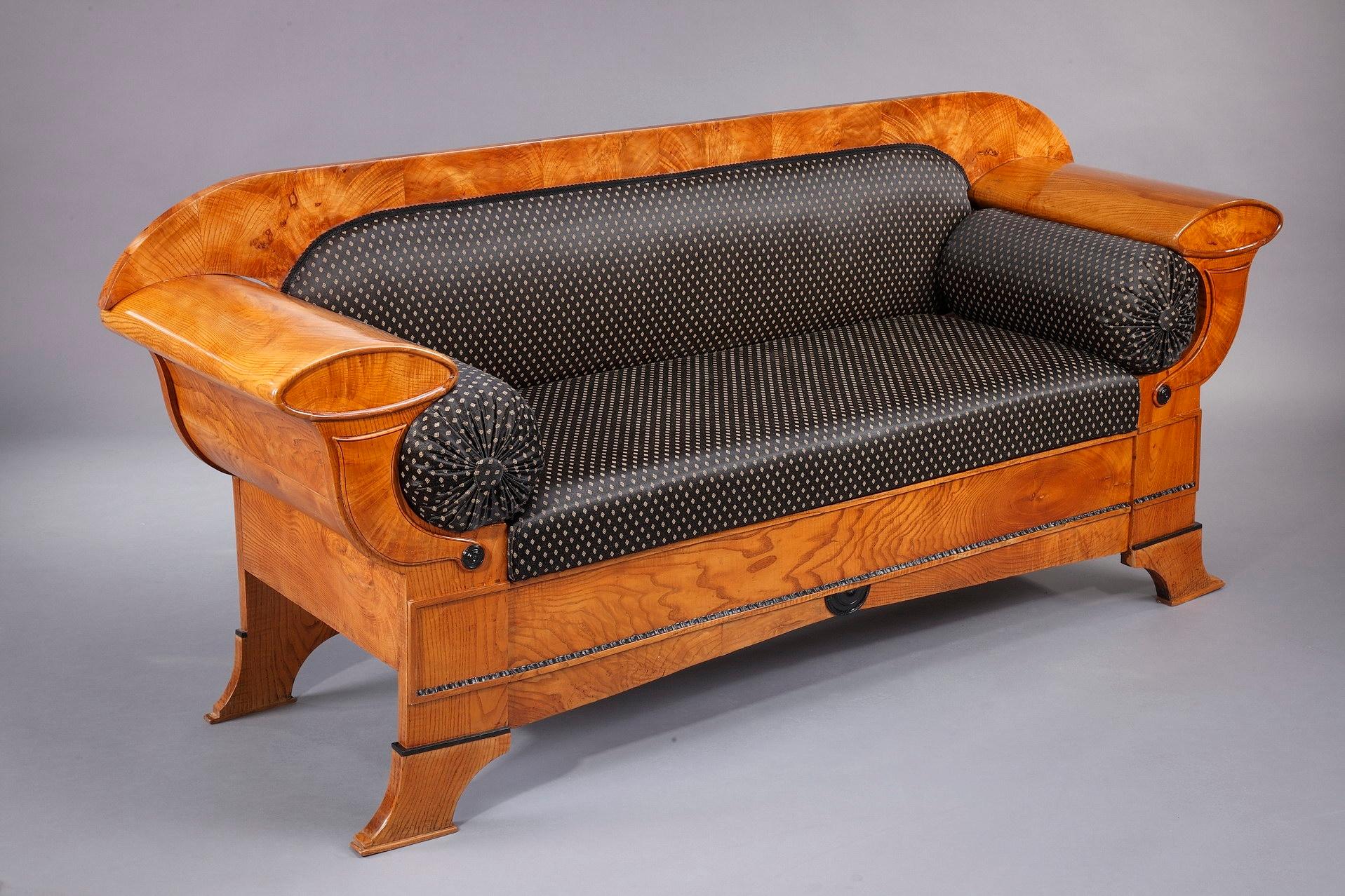 This Vienna Biedermeier sofa is crafted of oak veneer in Austria in the 1830s. Carved with elegant curving lines and cornucopia, it is a masterpiece of the Biedermeier style (1815-1848). The settee features an intricately detailed decoration of