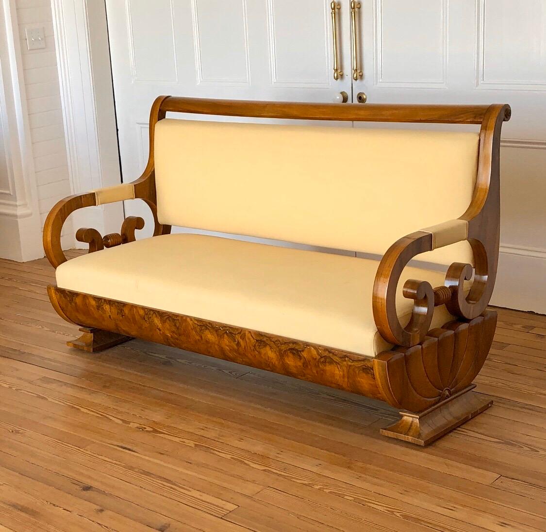 This elegant Biedermeier sofa has concave molded plinth bases, supporting a carved figural walnut scalloped fluted fan end with Grecian Scrolled arms. The seat rail has a beautiful bookmatched walnut veneer frieze. This Austrian Biedermeier sofa has