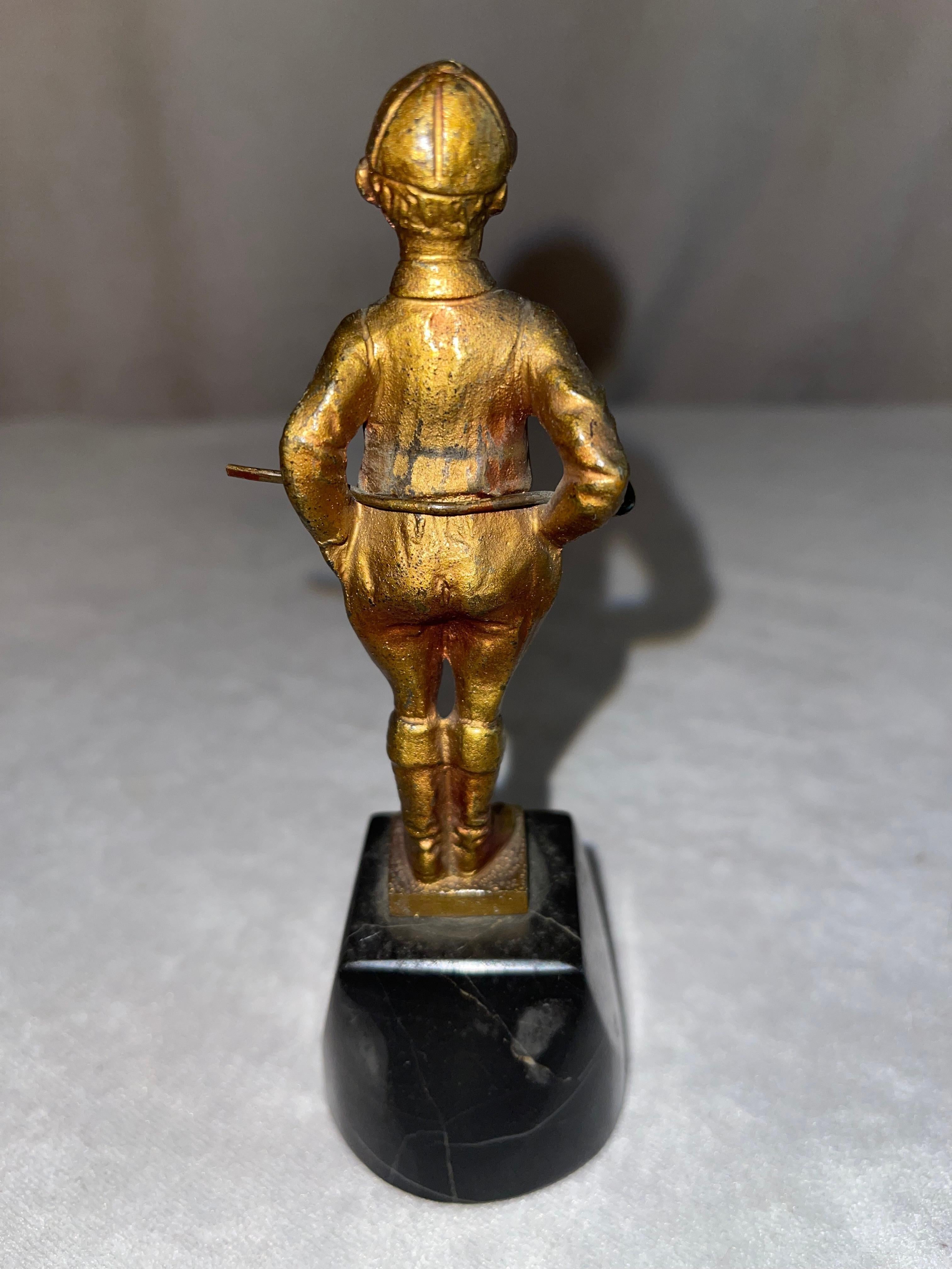 This finely cast bronze depicts a very young boy jockey standing with his original (yes original) crop. The crop has the same coloration as the boy's body. It was originally attached to his back, it has come loose, but has never left his possession,