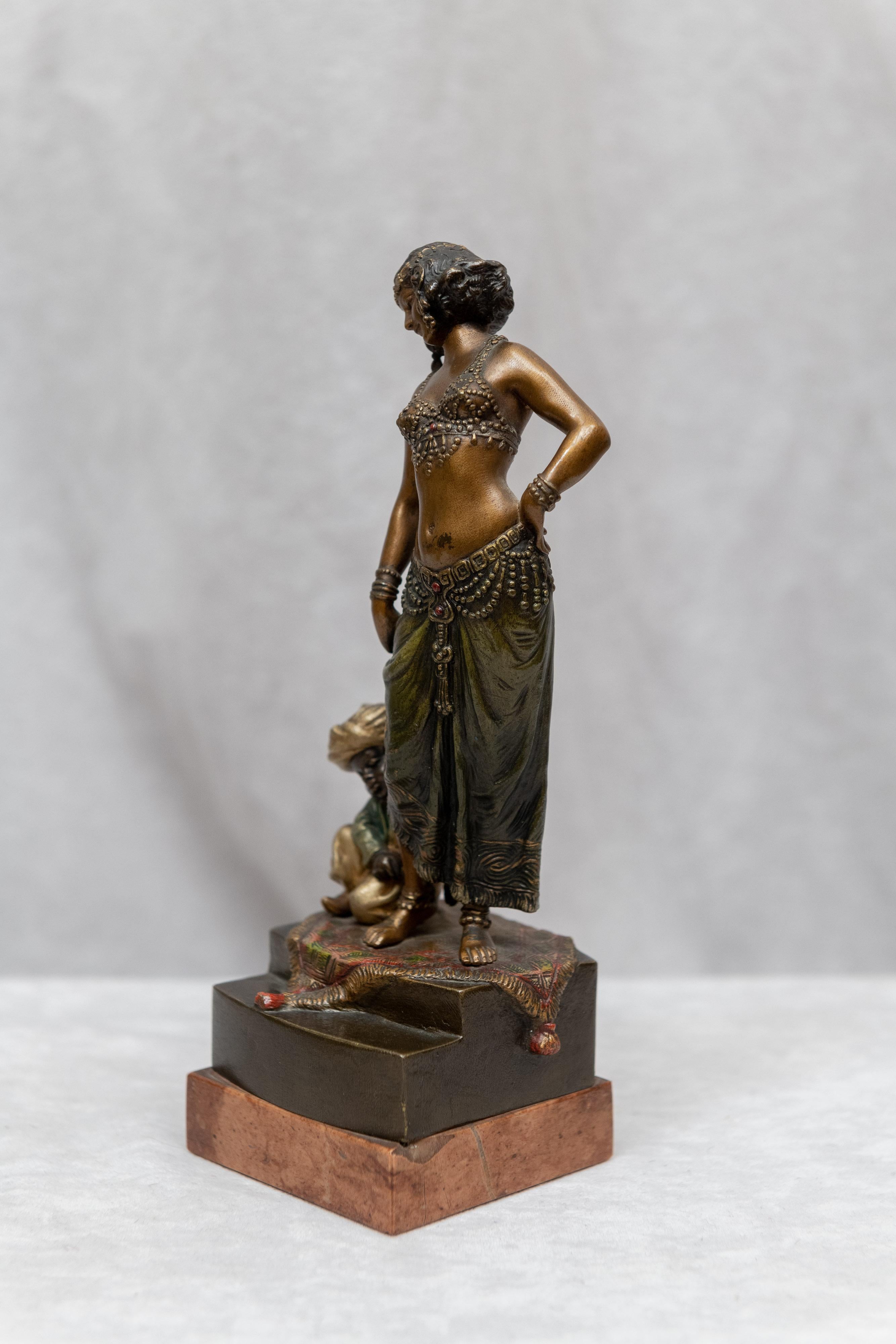 This very well modeled and attractive bronze is a fine example of the work of the Bergmann Foundry. 
The woman here is beautiful and the little boy is adorable. The boy is enjoying putting an ankle bracelet on this beauty. A joyful and colorful