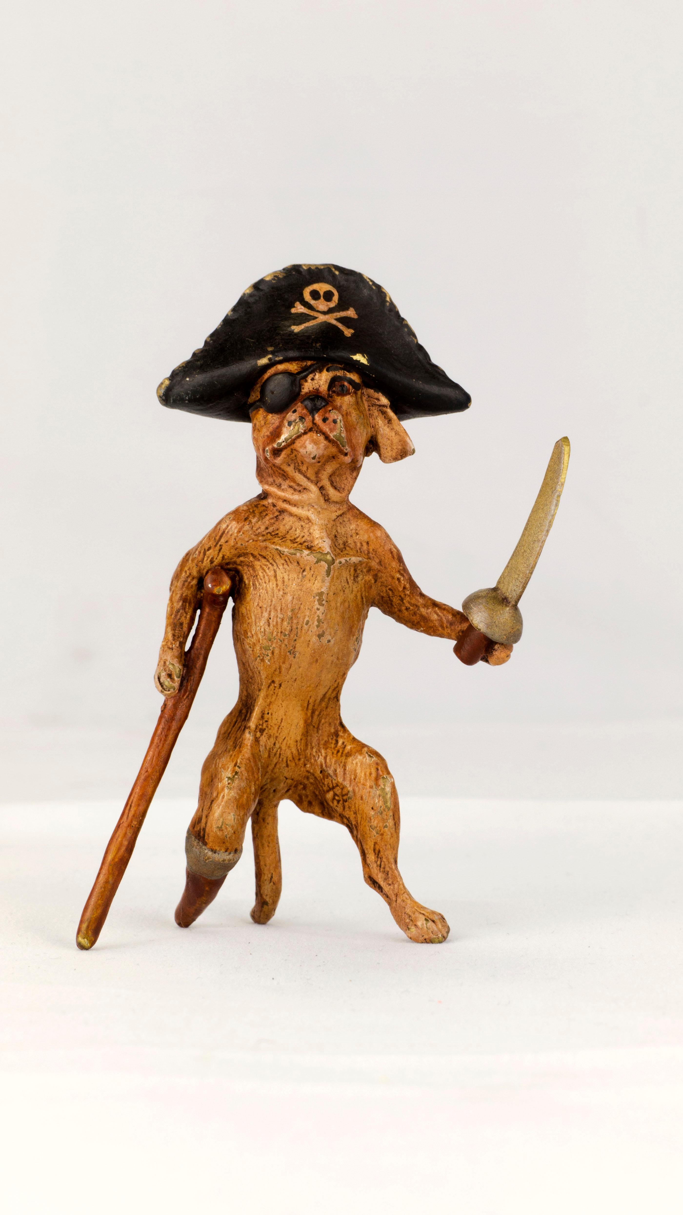 Franz Bergman - Standing Pirate Peg Leg Pug dog - Marked with a B in the Urn Cold Painted Bronze, Brown Dog with a Black and Silver Hat, a silver colored Sword, and a yellow head band. Made in Vienna Austria, circa 1900s MEASURES: 4.5 inches long An