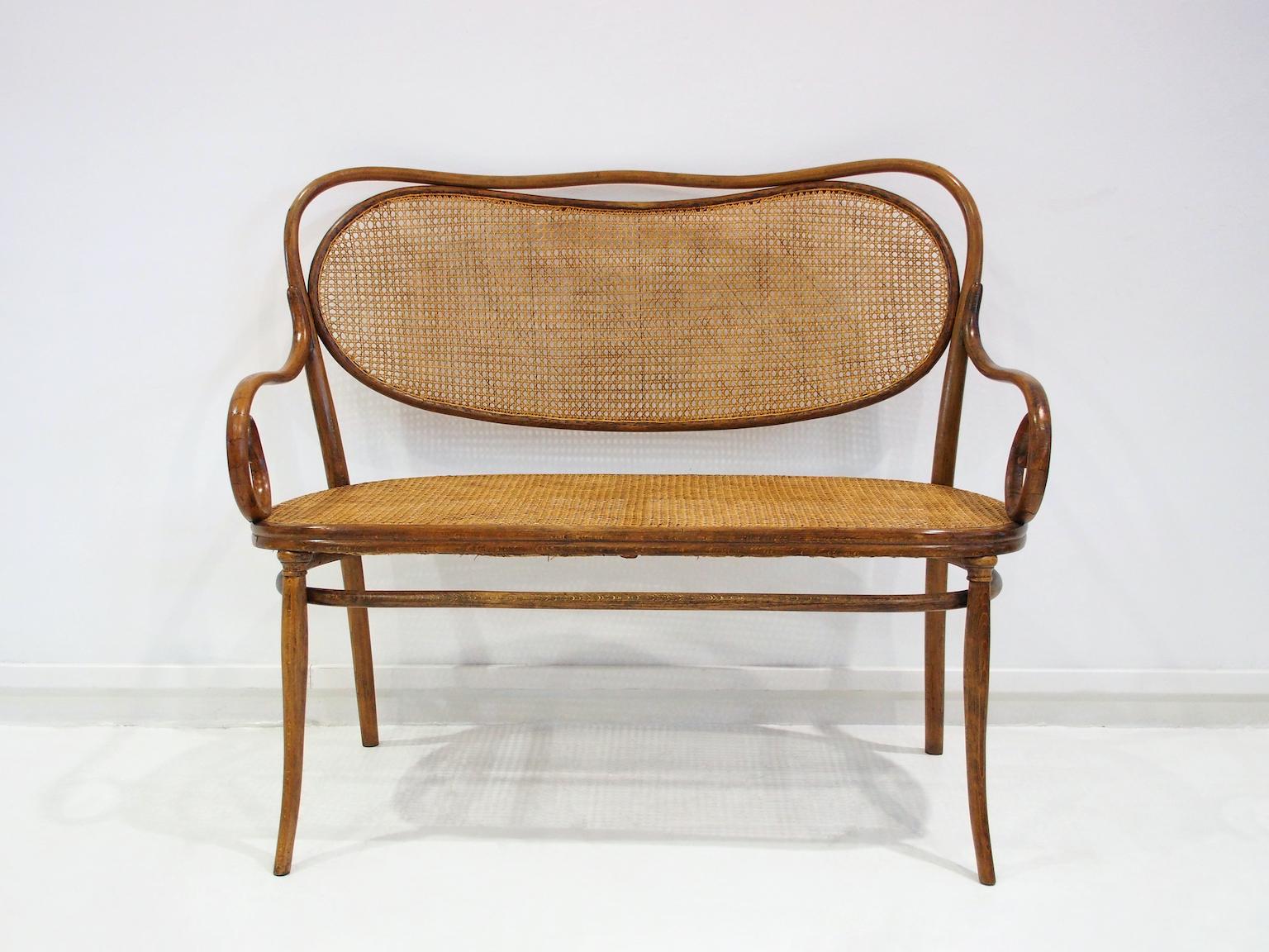 Rare Vienna Secessionist bentwood and rattan settee by Thonet Brothers. The settee can be found in old Thonet catalogues and based on the paper label underneath, the seat was manufactured between 1870 and 1881. The settee is in good condition and