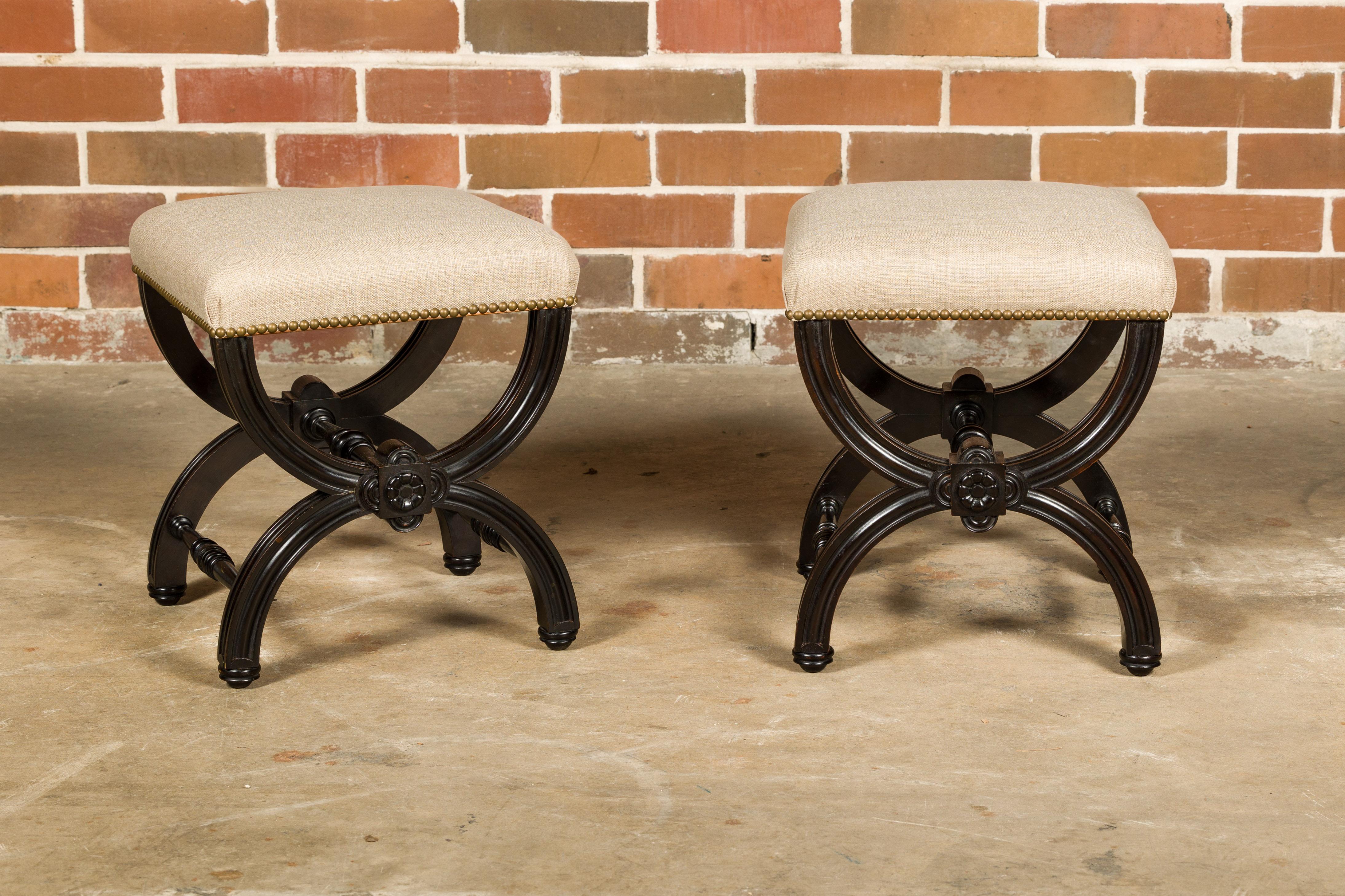 A pair of Austrian 1900s black stools from Vienna with X-Form bases, turned stretchers and new custom linen upholstery. These early 1900s Austrian black stools hailing from the cultural hub of Vienna are a testament to the city's rich tradition of