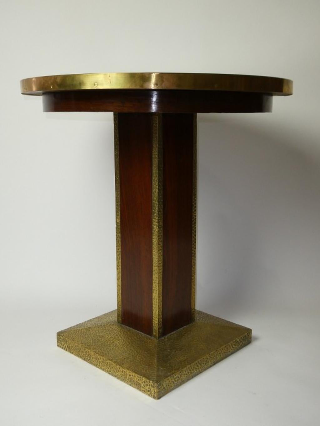 Square base table with wrought iron hoof plate, hammered Viennese decor. Mahogany wood column flanked by wrought iron sheet with hammered decoration. Plateau lined with brass, inset faceted thick-walled glass.