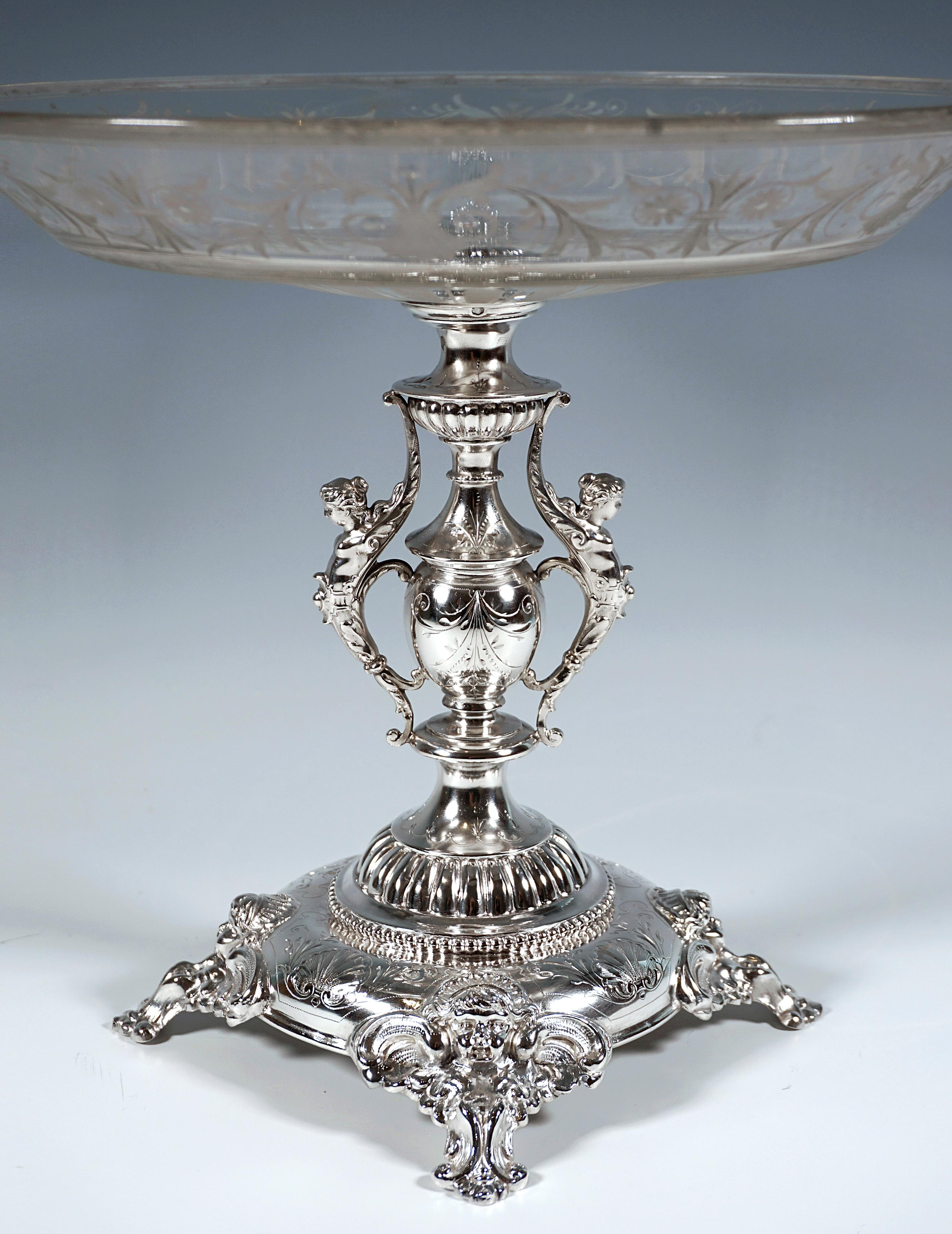 Elegant silver centerpiece on a round, multi-stepped curved base with four square rocaille feet with putti heads in relief, finely chased shell and floral decoration, baluster-shaped shaft with chased trim and leaf festoons, on the sides, opposite