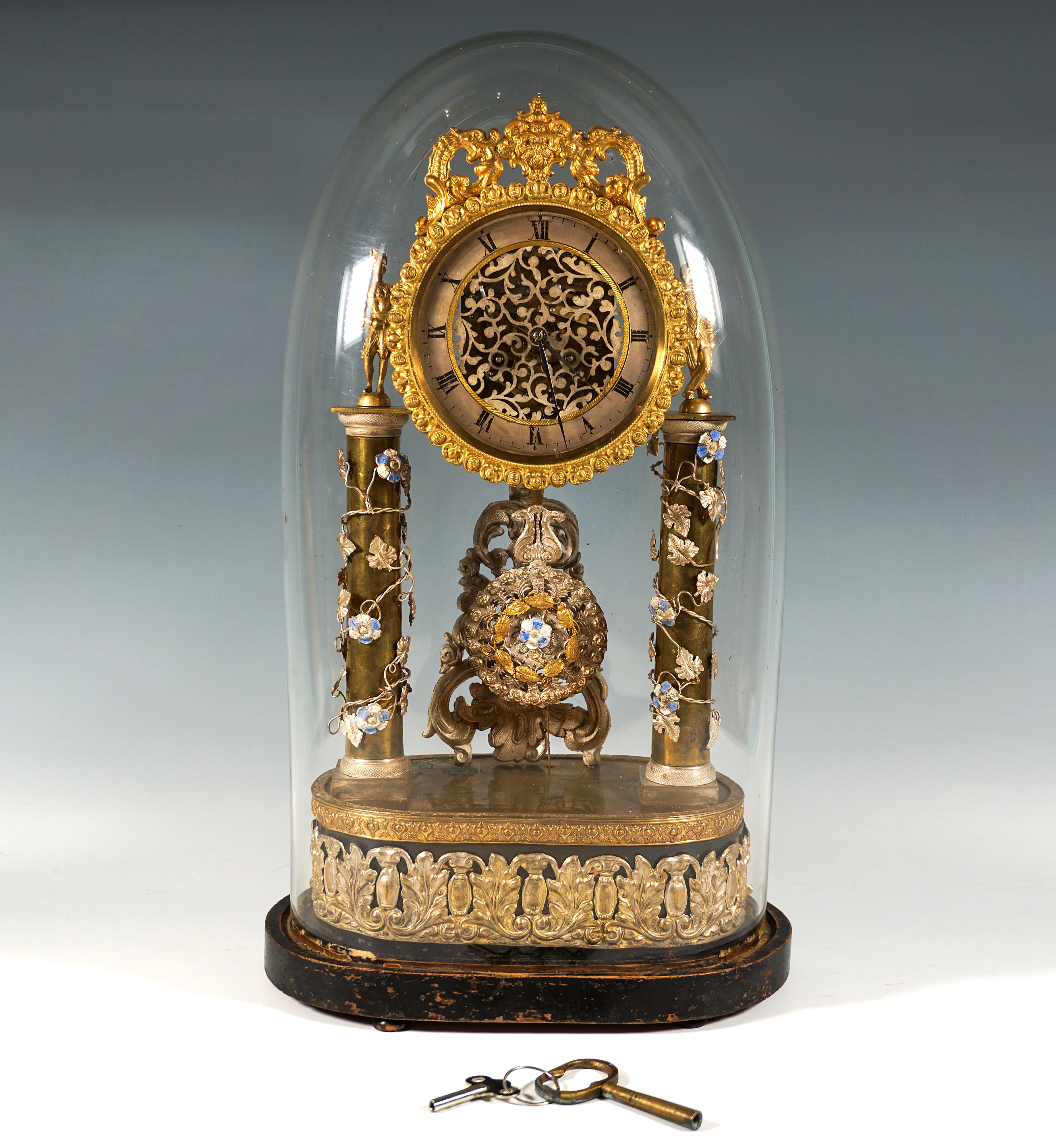 La mejor artesanía vienesa:
Bajo la cúpula de cristal original, la base ovalada de madera ebonizada sobre cuatro pies de bollo, con mecanismo musical que suena automáticamente a las horas, cuerpo de madera con herrajes de latón plateado con