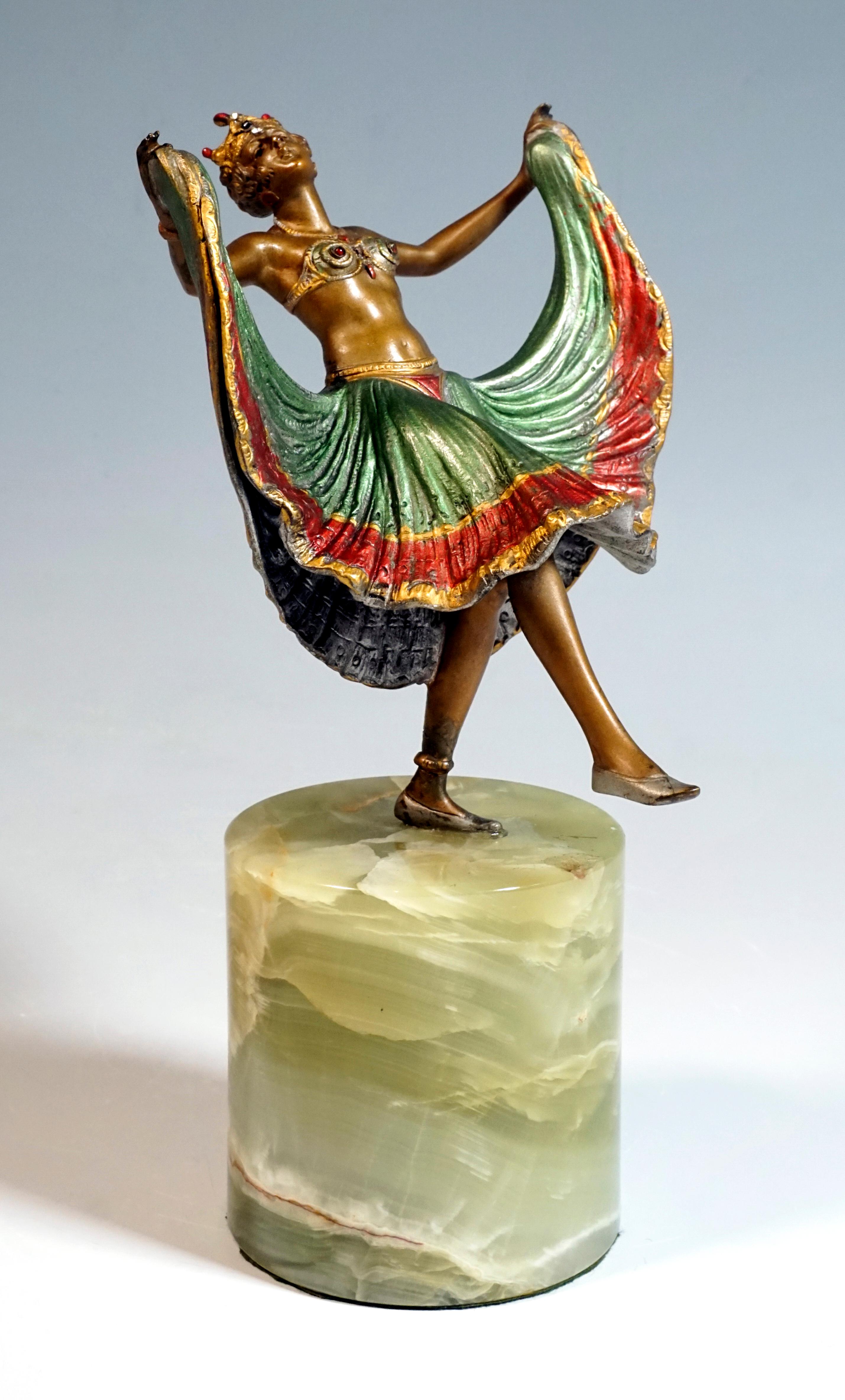 Young dancer in an oriental-style costume with a tight bustier, a wide skirt and a diadem set with gemstones, in a position leaning backwards, lifting the right leg forward and holding the skirt up like a fan at the side.
The figure is decorated in
