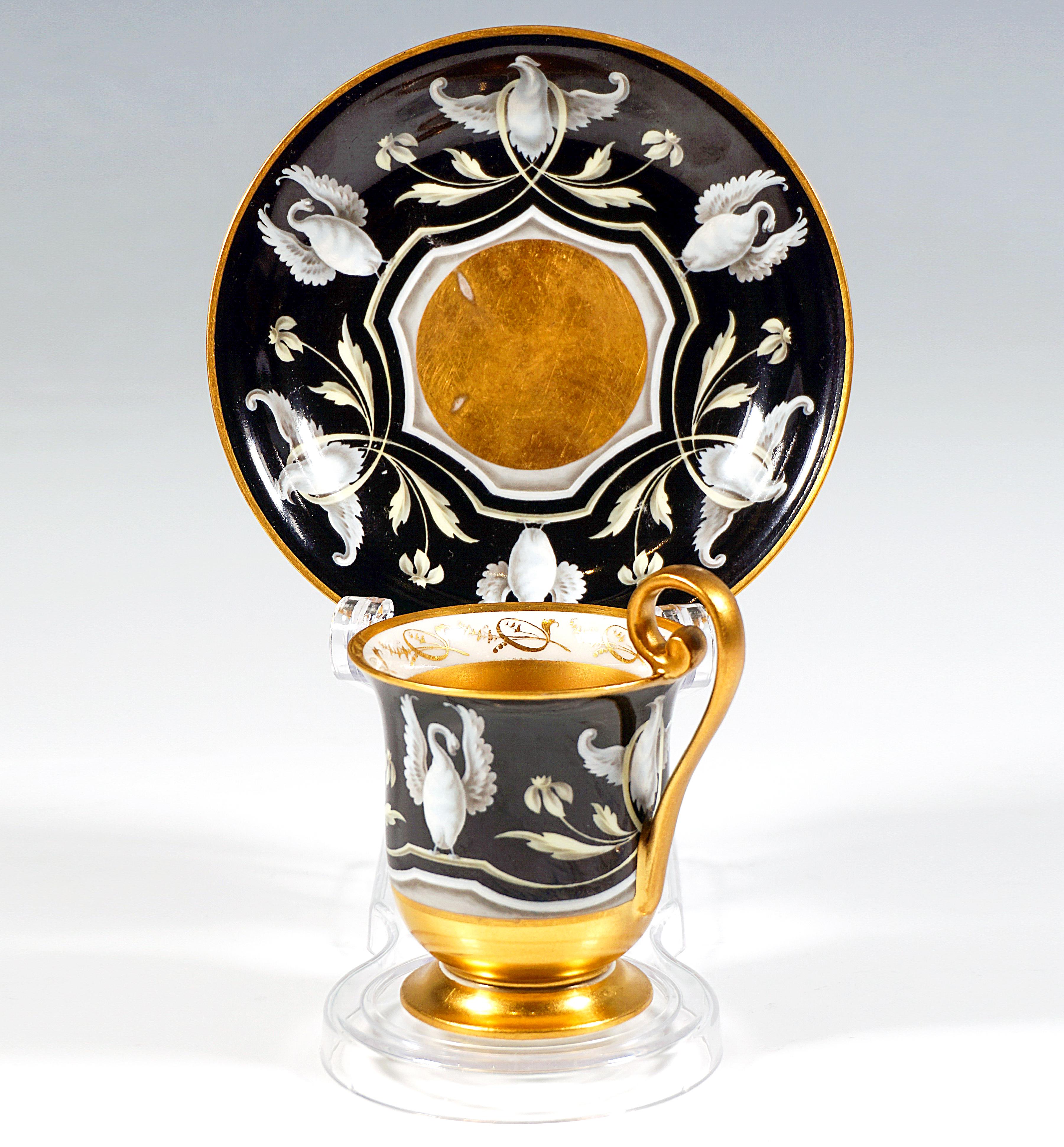 Taza con platillo de porcelana vienesa antigua extraordinariamente decorada:
Copa acampanada de porcelana blanca sobre pie escalonado, tres cuartas partes del exterior decoradas con estilizados cisnes y delicada decoración floral y de hojas en