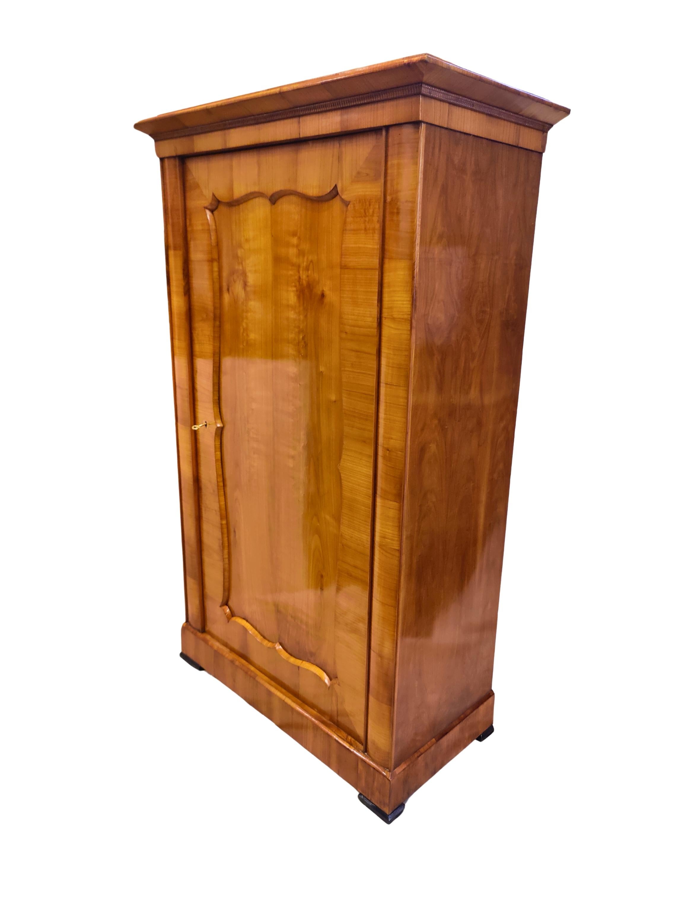 Elegante armario vienés de estilo Biedermeier tardío de hacia 1850, chapado en madera de cerezo bellamente labrada sobre un cuerpo macizo de pícea. La puerta única está enmarcada por una característica moldura en forma de 