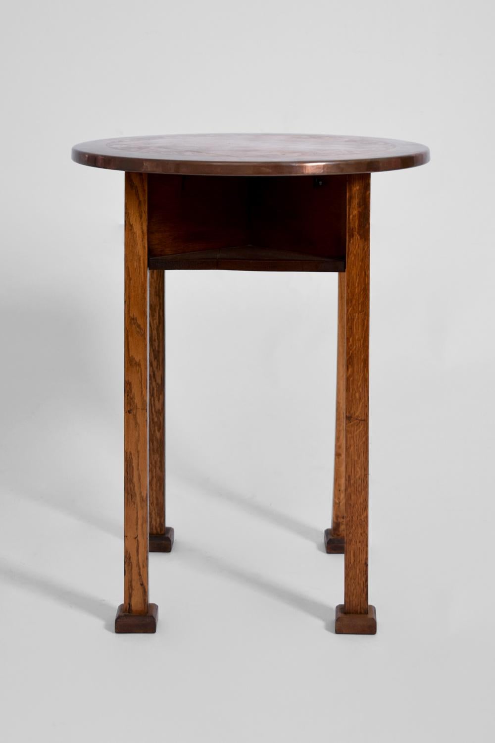 Guéridon ou table d'appoint de style sécession viennoise. Structure en bois massif avec quatre niches pour ceinture. Plateau en cuivre gravé d'un échiquier et de motifs floraux Art Nouveau sur le cadre.