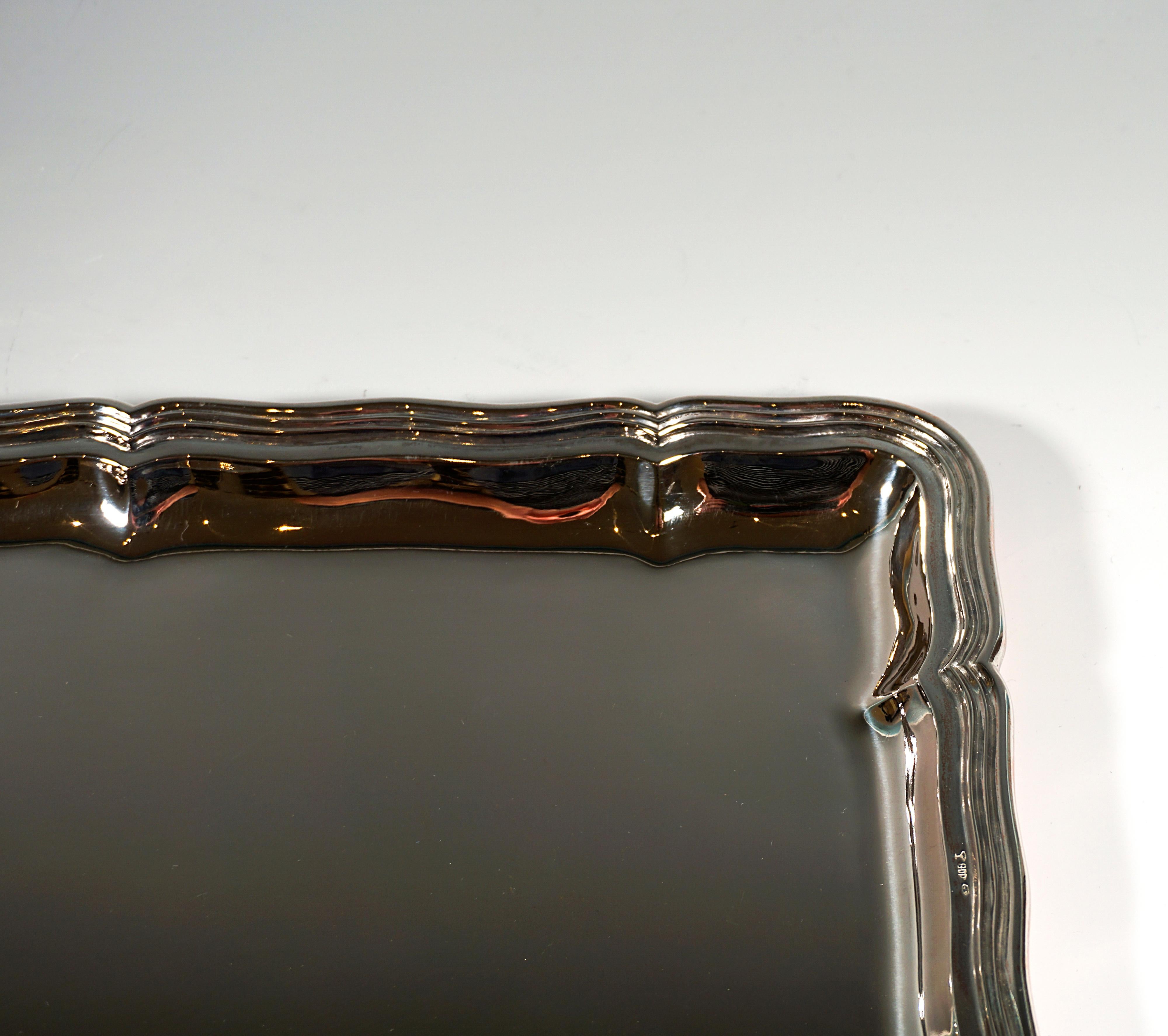 Plato de plata de forma rectangular con un diseño liso y sencillo y un borde ondulado y perfilado. Grabado del platero en la parte inferior.

Obra maestra de sencilla elegancia del fabricante vienés de plata 