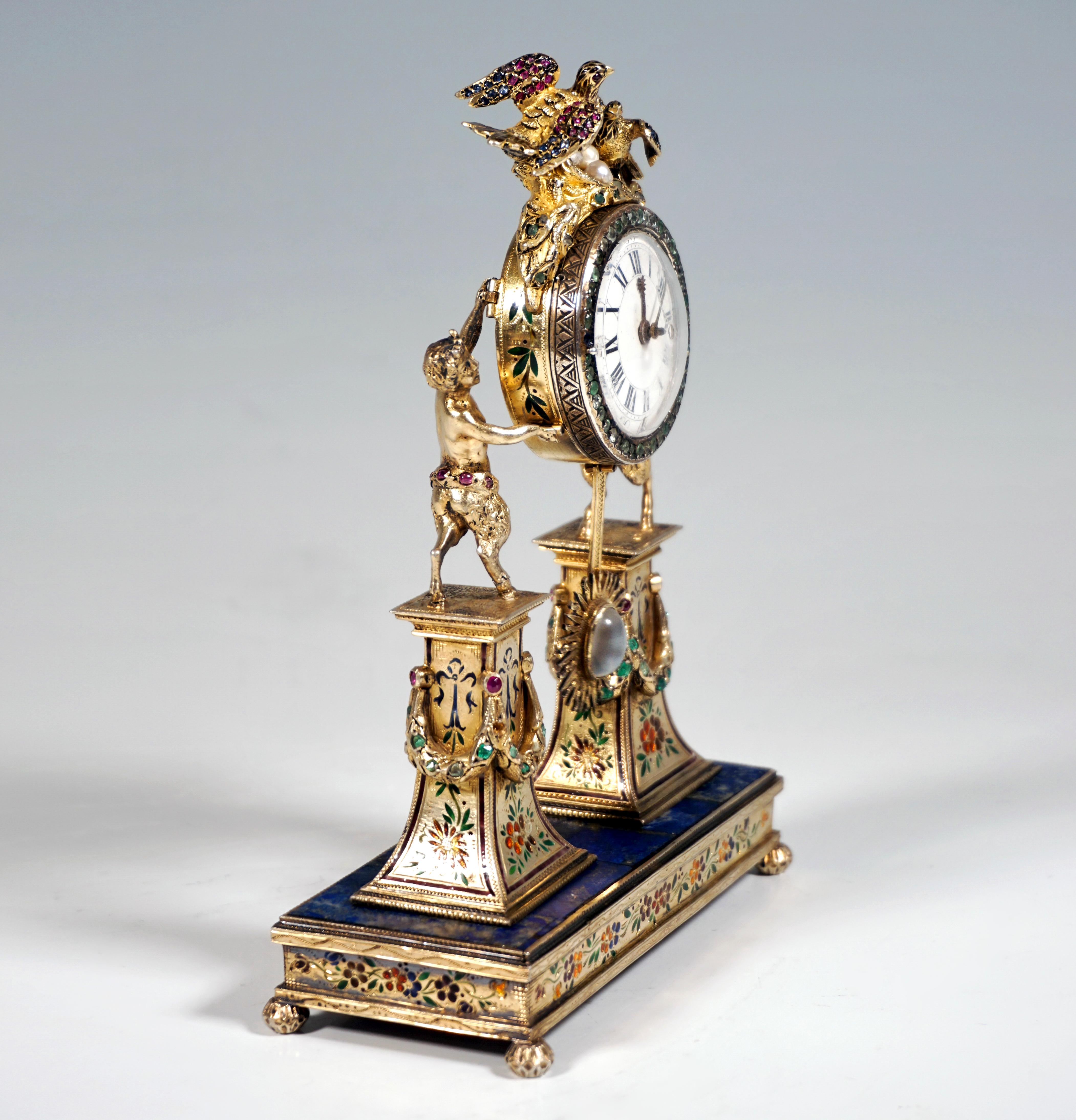 Artfully decorated silver clock by a Viennese master:
On a rectangular base plate on four ball feet, two pedestals narrowing towards the top and decorated with wreaths, on these two fauns carrying the drum-shaped clock case aloft, clock crowning