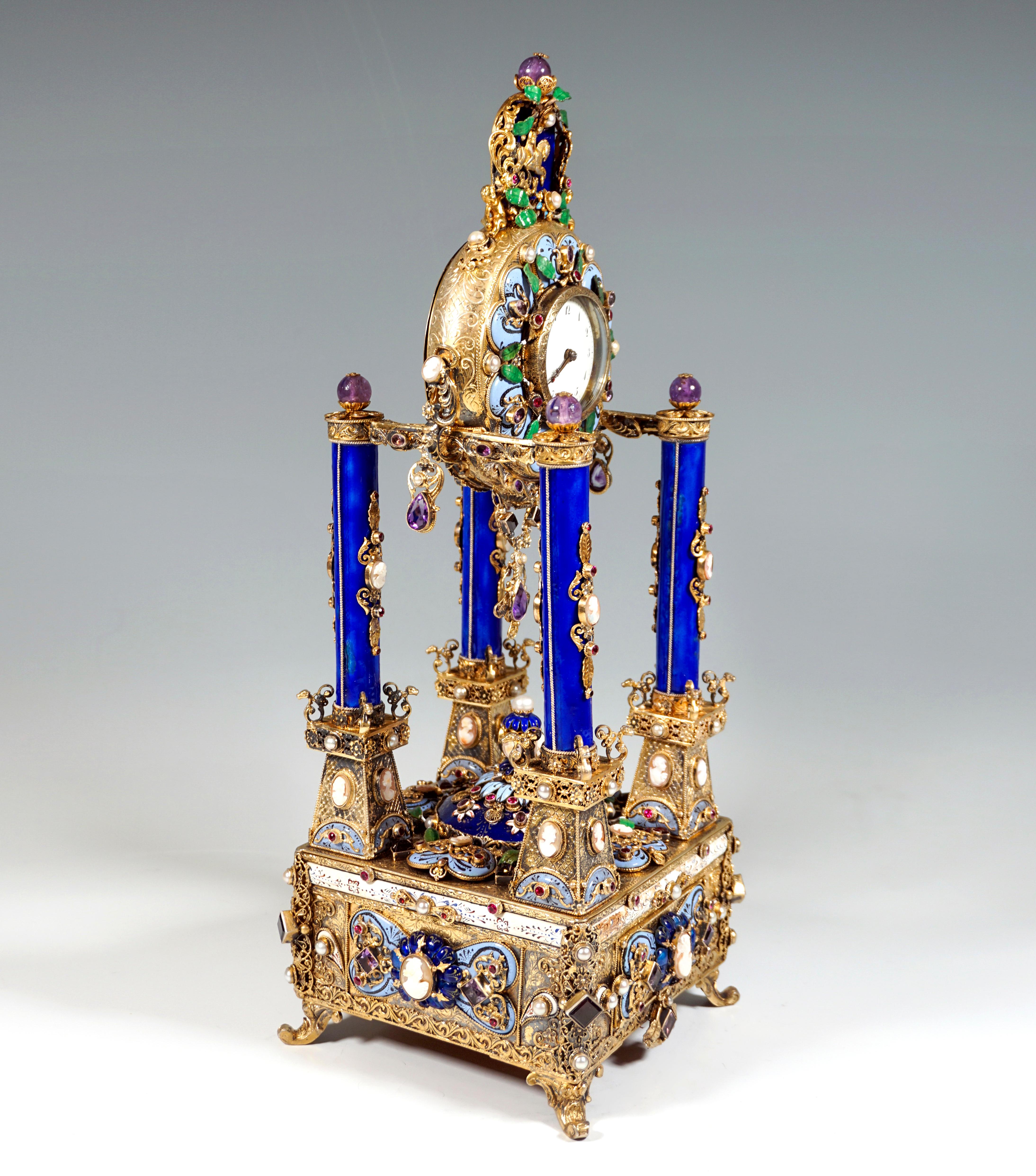 Artfully decorated silver gilded table clock by a Viennese master: 
The base body made of silver, containing the musical mechanism, standing on four volute feet over a square plan, gilded surface chased and densely covered with reliefed and fully